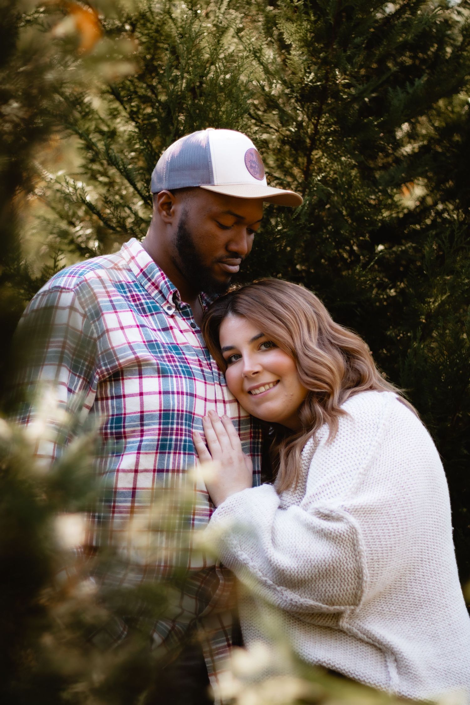 A couple shares intimate moments outdoors in a series of romantic photos featuring plaid and a cozy white sweater.