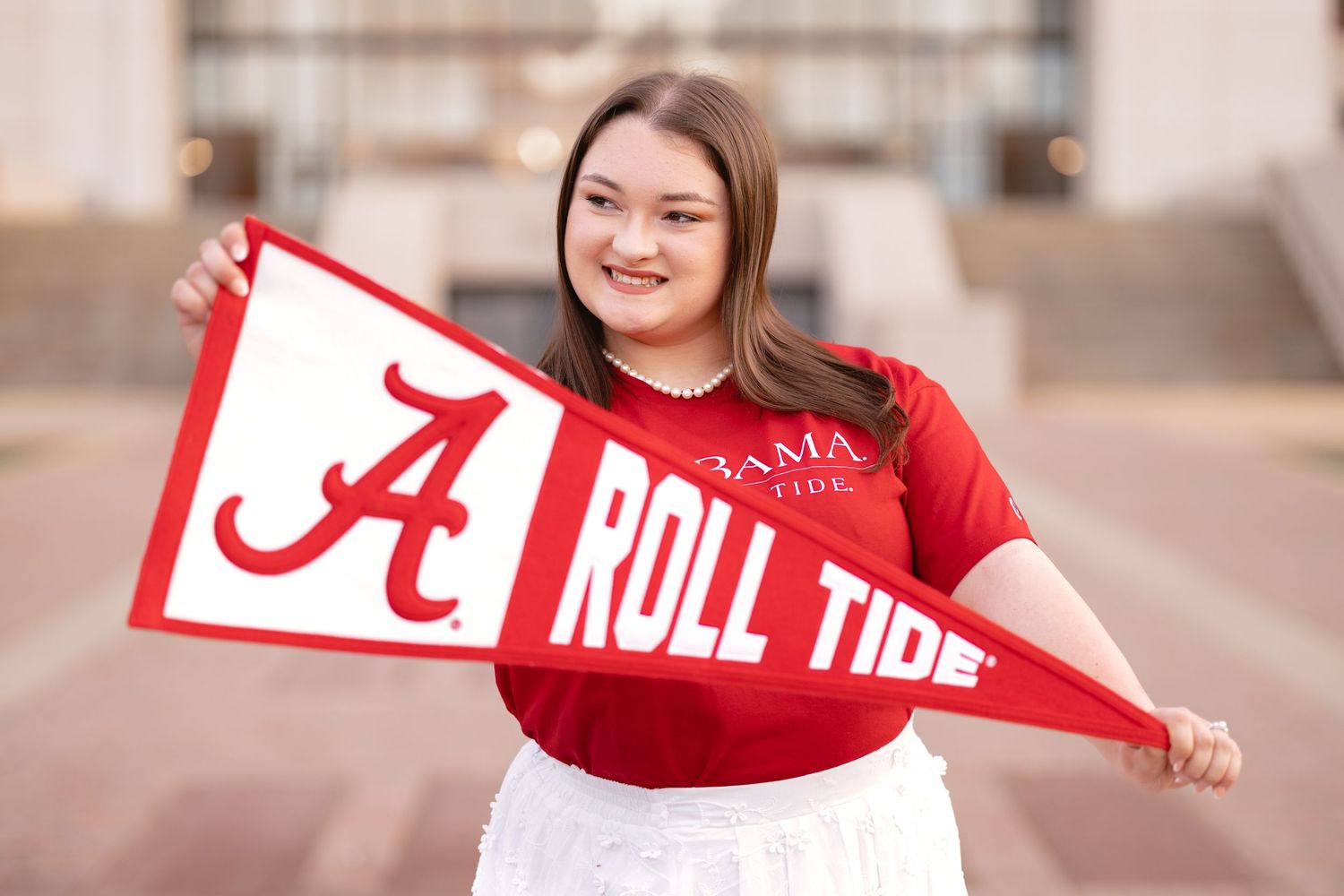Someone displays a red and white Alabama Roll Tide pennant flag with enthusiasm.