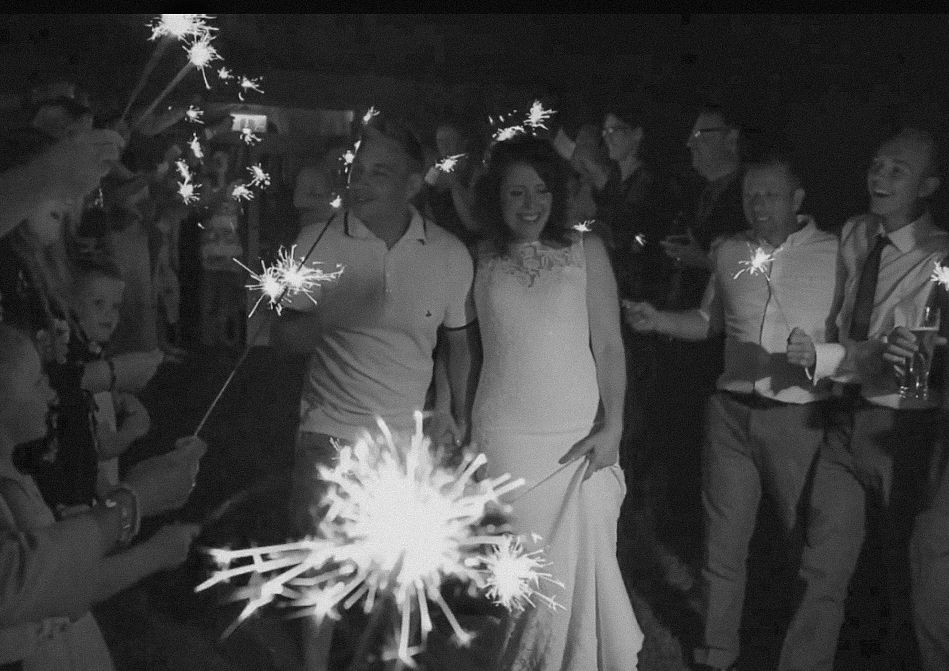 People holding sparklers creating light trails in the dark at a celebration.