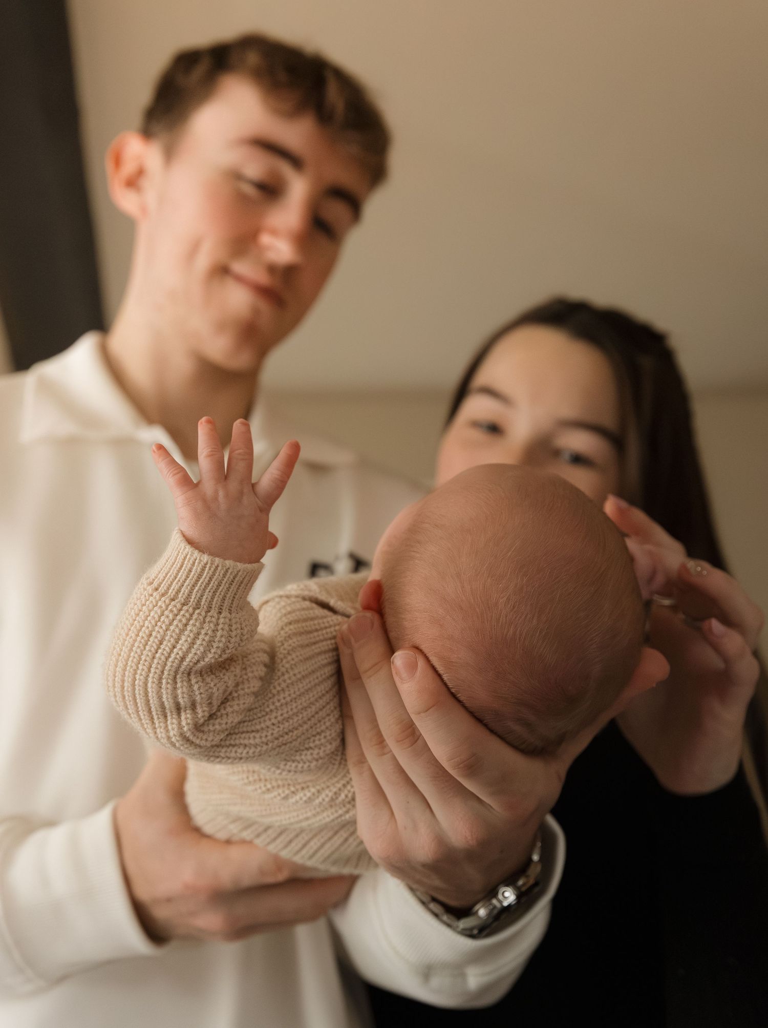 A series of photos showing a newborn baby being gently cradled in someone's arms while wearing a knit sweater.