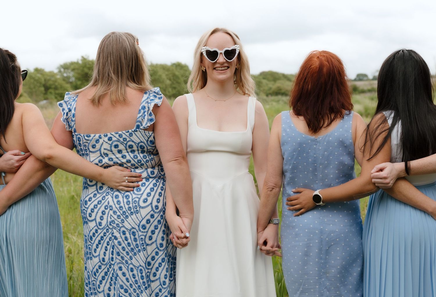 Row of women in coordinated blue and white dresses standing together outdoors.