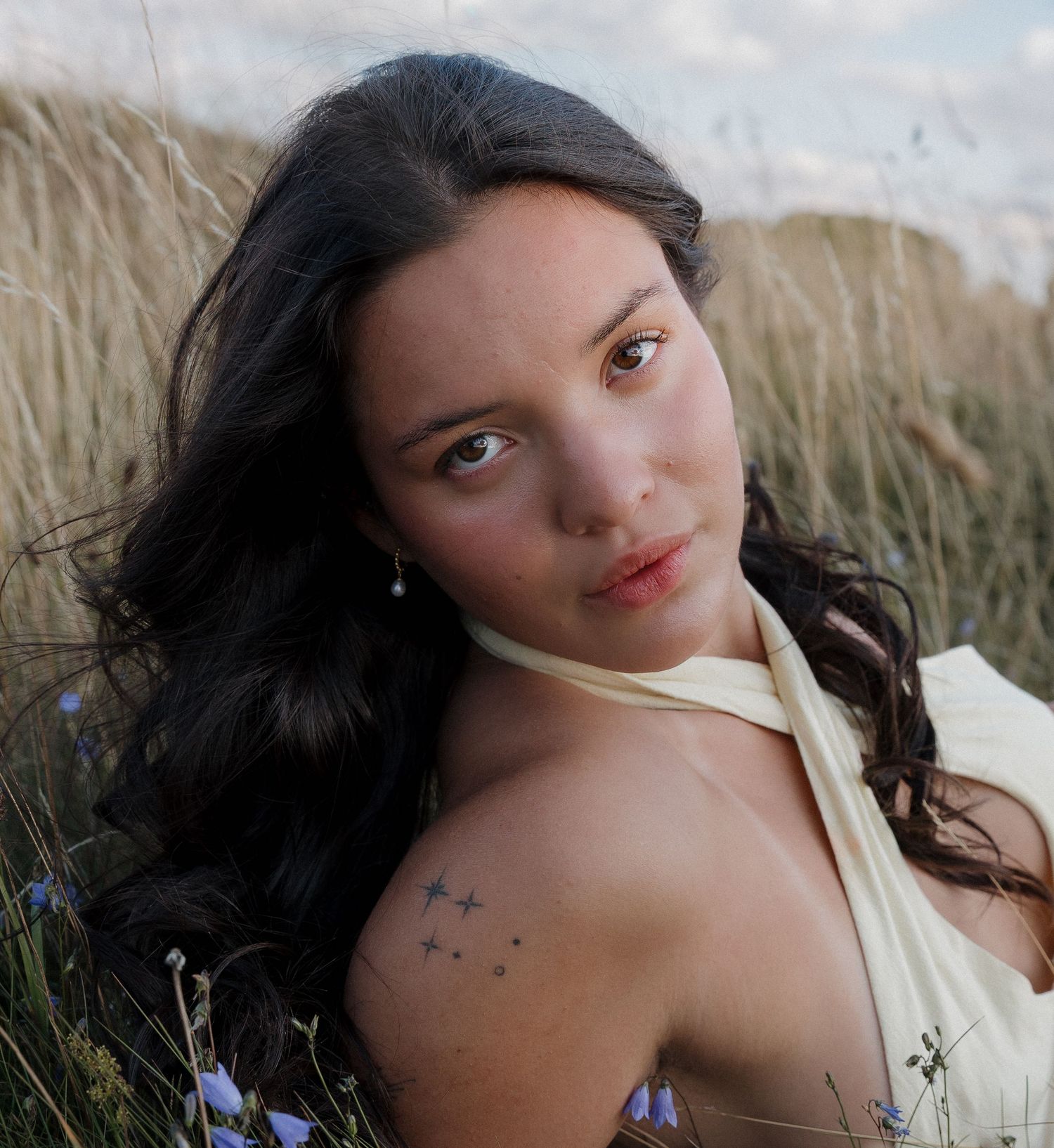 Artistic portrait shot among wildflowers and tall grass on an overcast day.