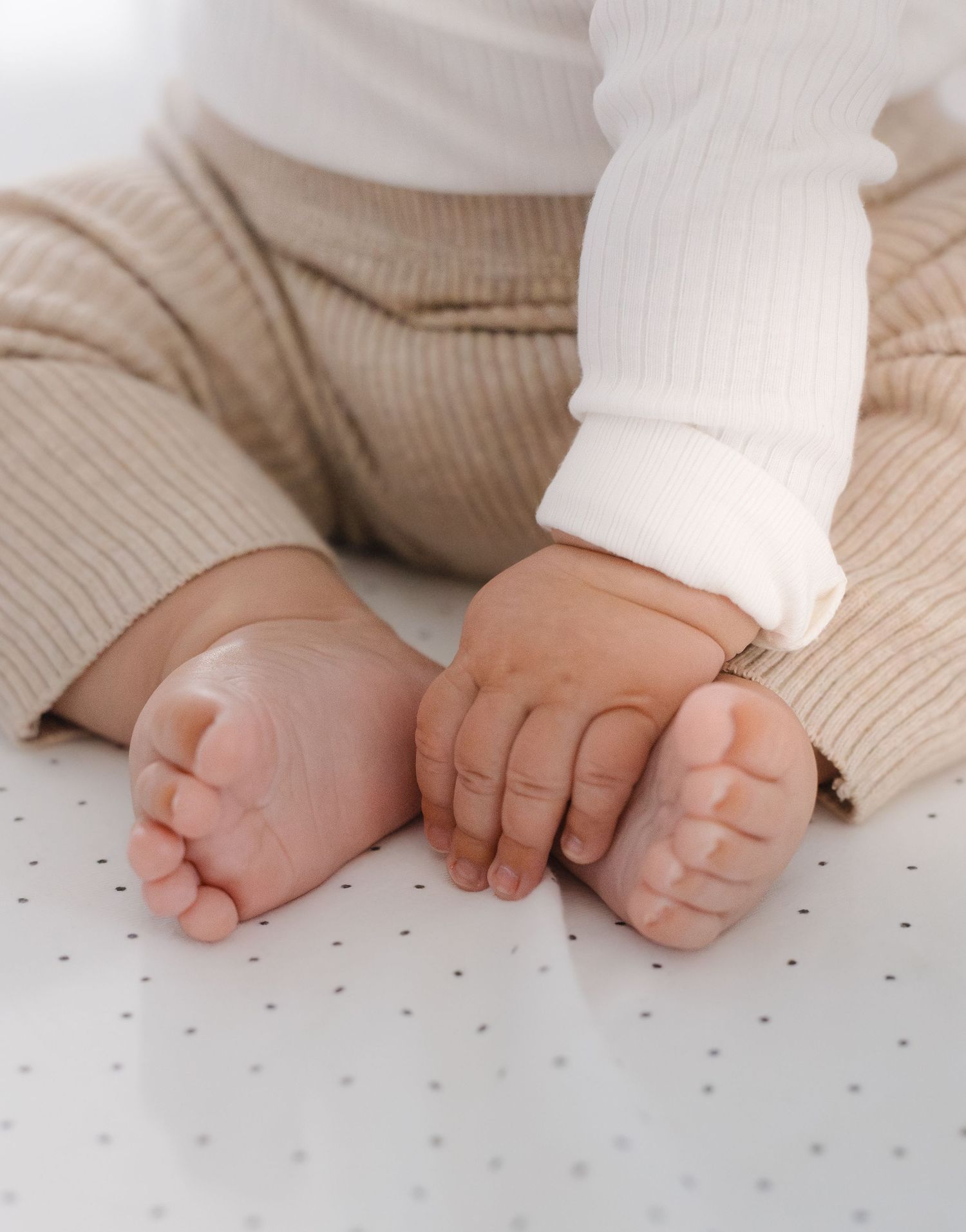 Baby's tiny hands explore a polka dot patterned surface in a series of progressive movements.