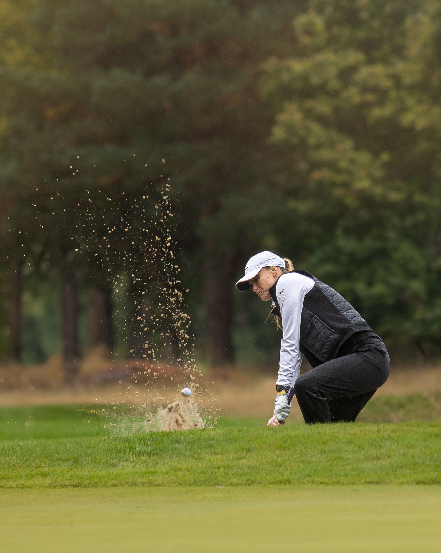 An ex Manchester city player in golfer in black and white clothing hits a bunker shot on a golf course at BMW PGA Championships.