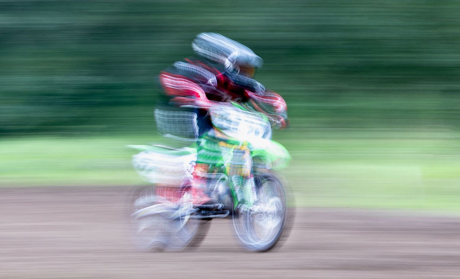 Sequence of motion-blurred motorcycle racing shots showing speed and movement on a green background track.
