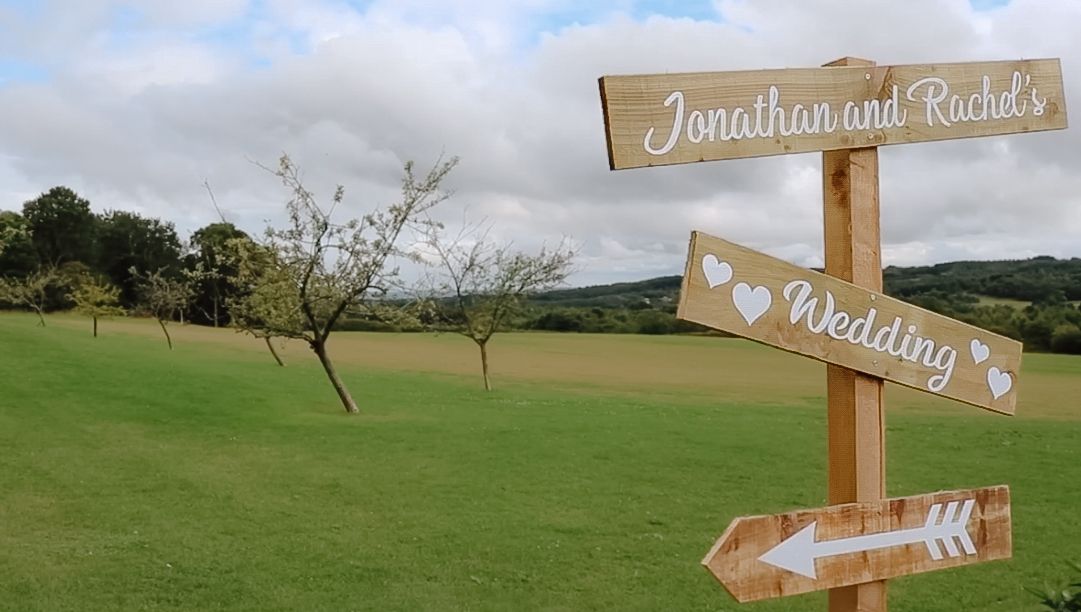Rustic wooden directional signs against a countryside landscape.