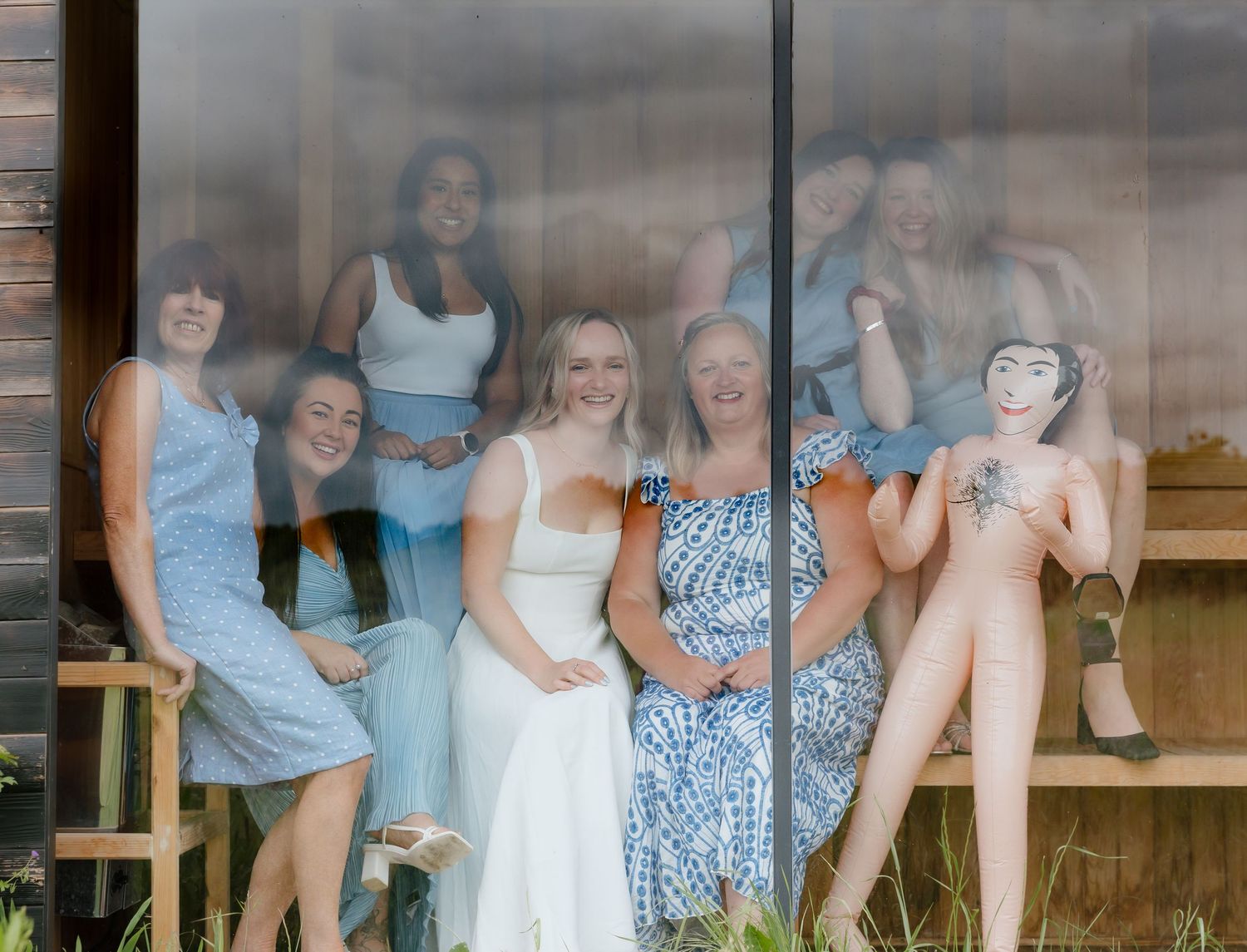 Friends in coordinating outfits share joyful moments on outdoor wooden bench.