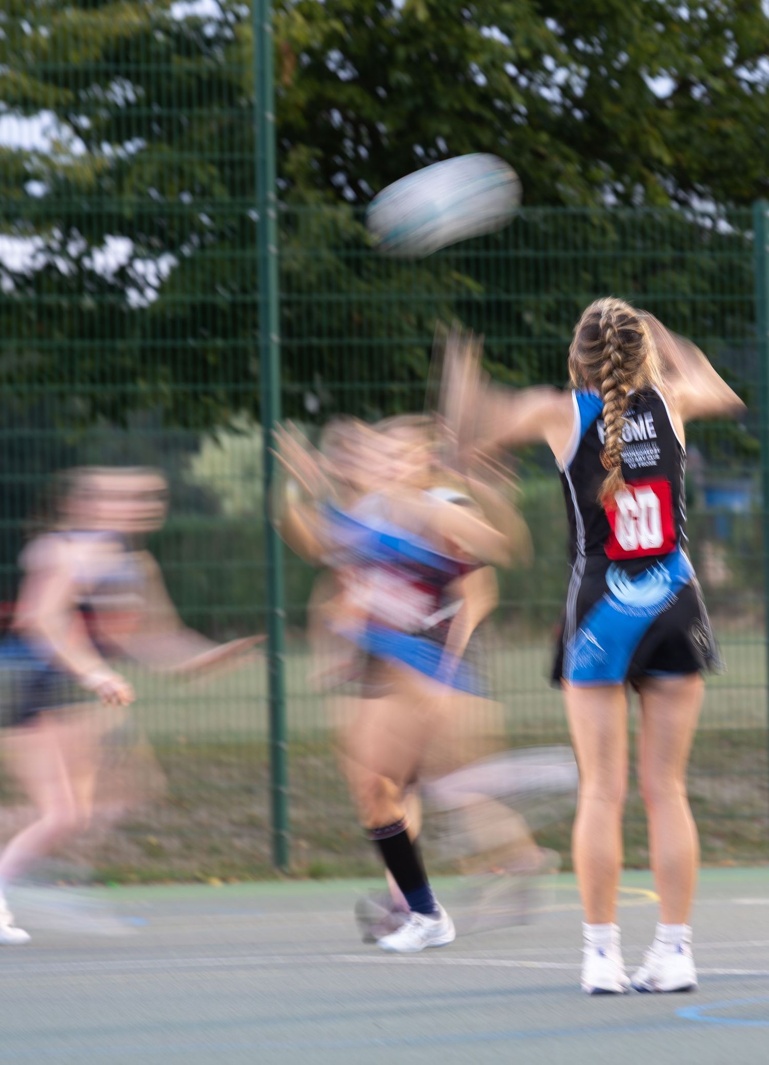 Motion blur capture of netball players practicing on outdoor court.
