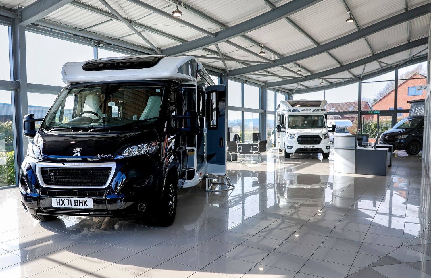Modern car showroom interior with luxury vehicles on display under bright lighting.
