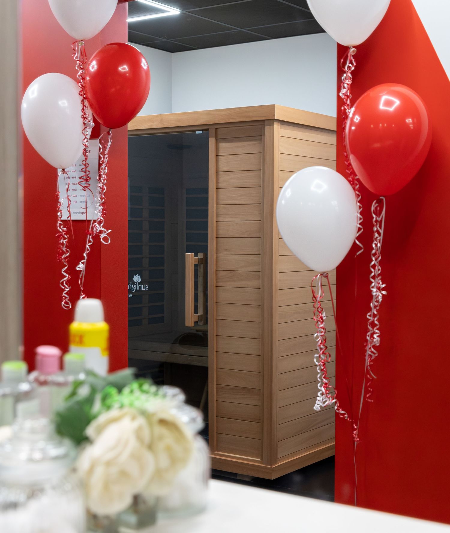 Festive decoration with red and white balloons against red wall in office space.