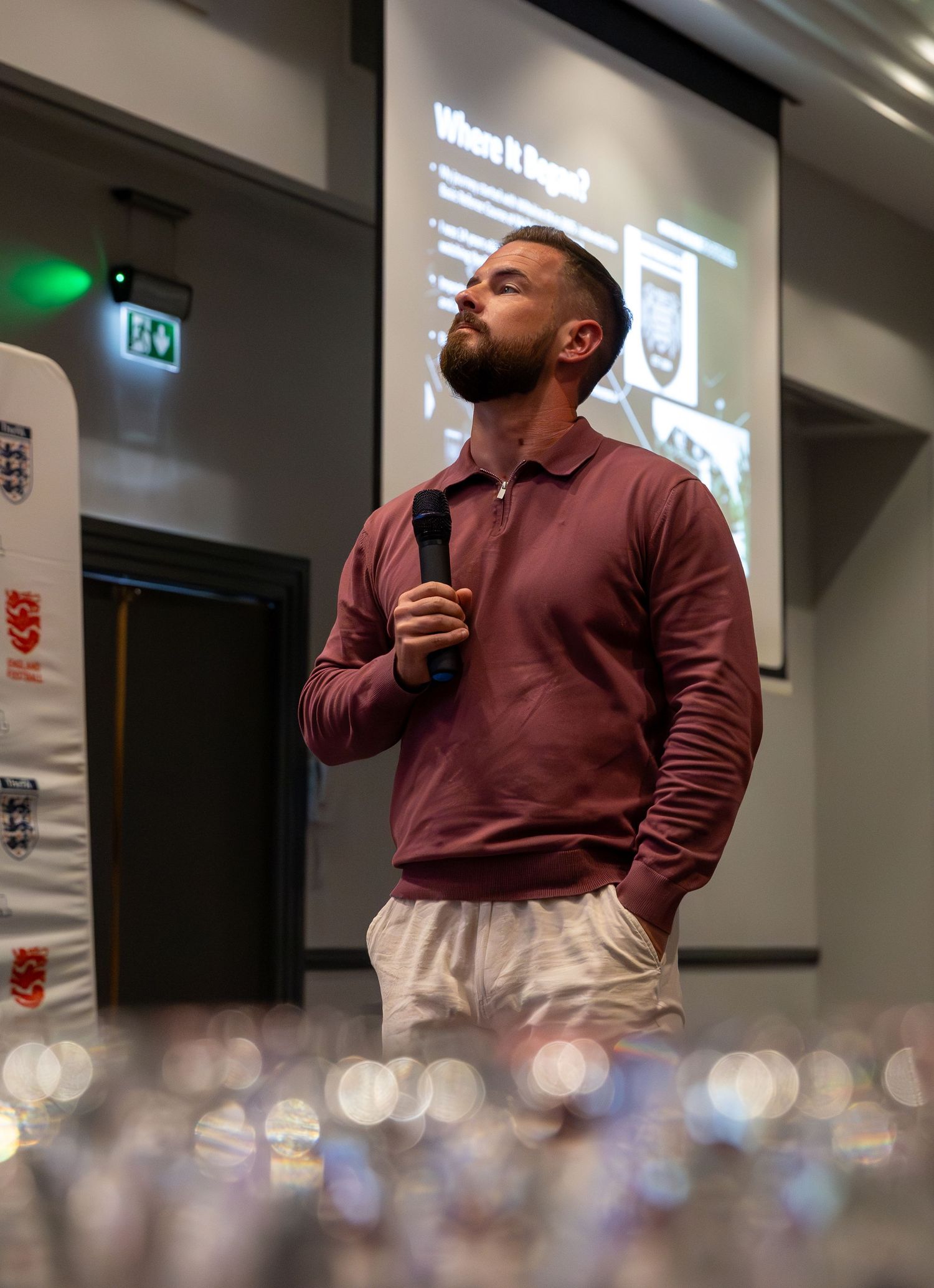 A person in burgundy sweater speaking at a presentation event.