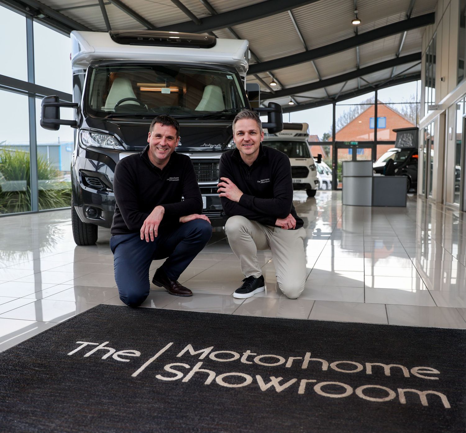 Car showroom display area with vehicles on raised platforms and clean, modern aesthetic.