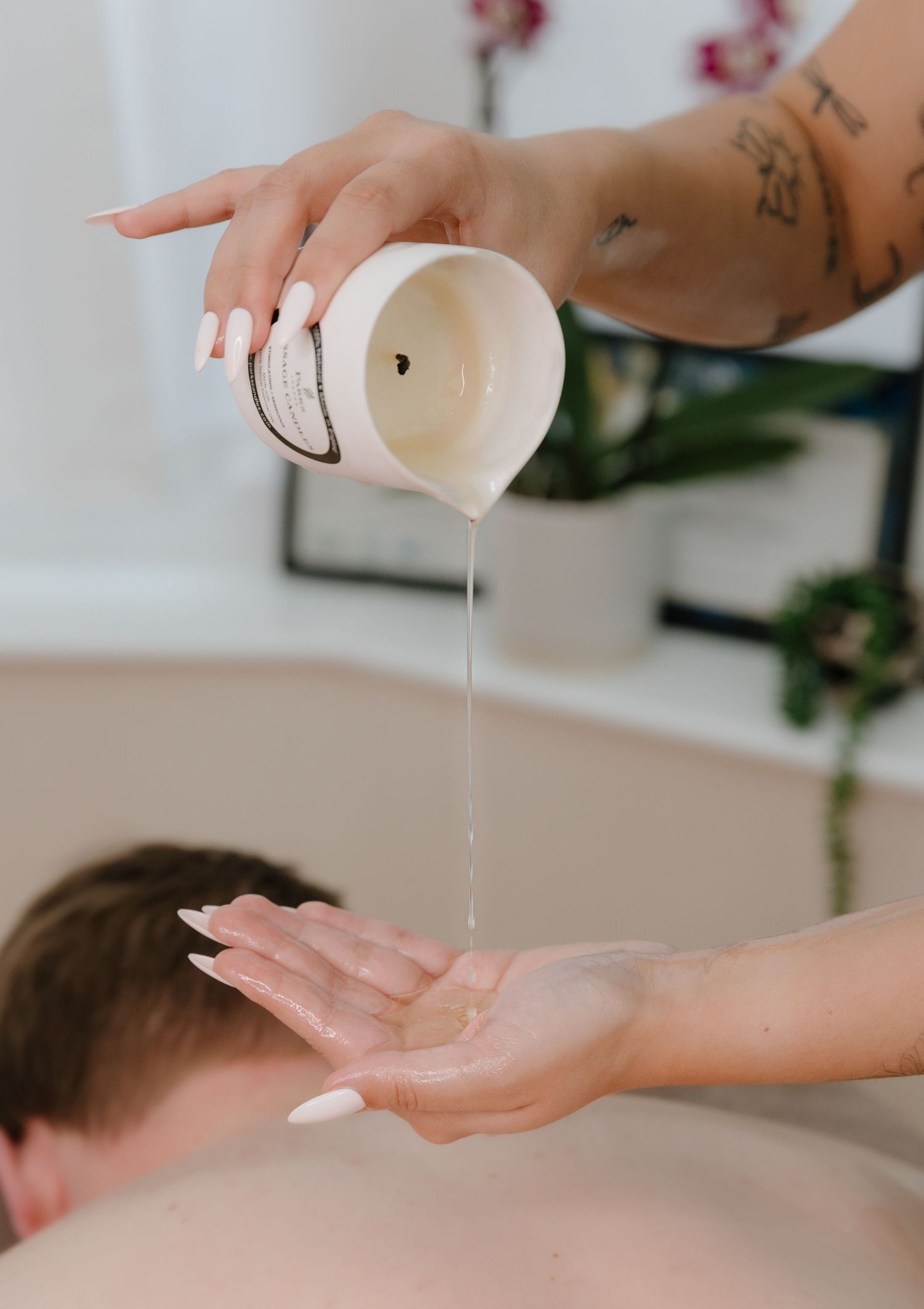 Massage therapist pouring massage oil onto hands during spa treatment.