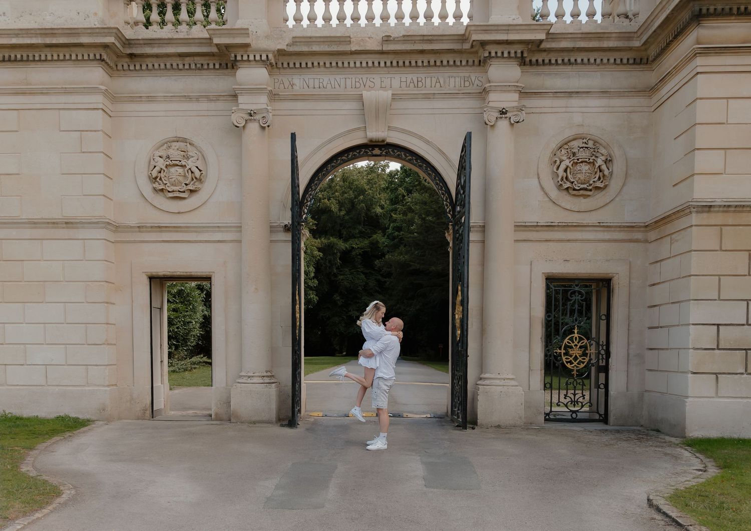 Wide architectural shot of an elegant stone building entrance with ornate gates and columns.