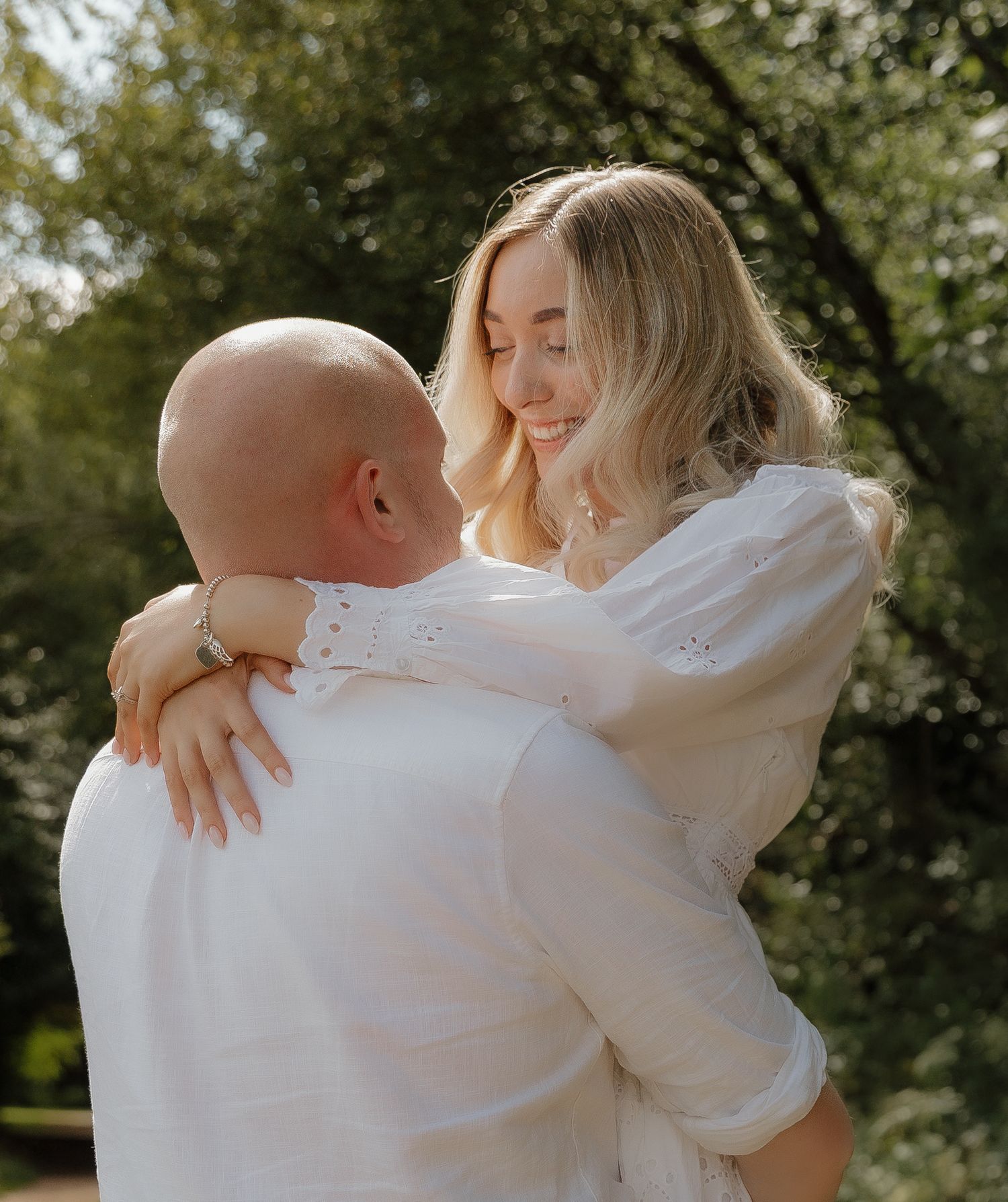 A tender embrace captured in warm sunlight filtering through trees.