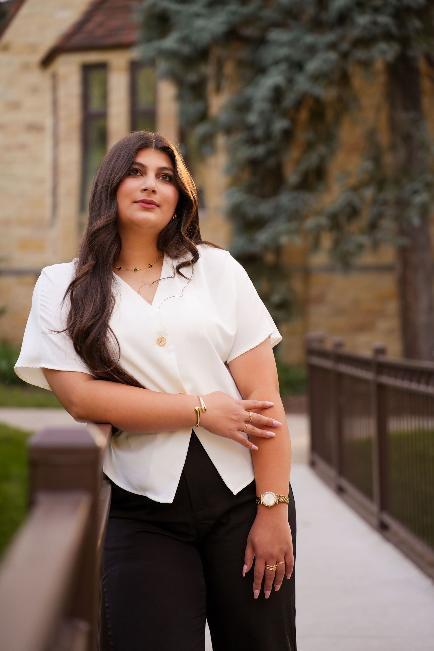 Professional portrait of a woman in business attire standing confidently against a stone building.
