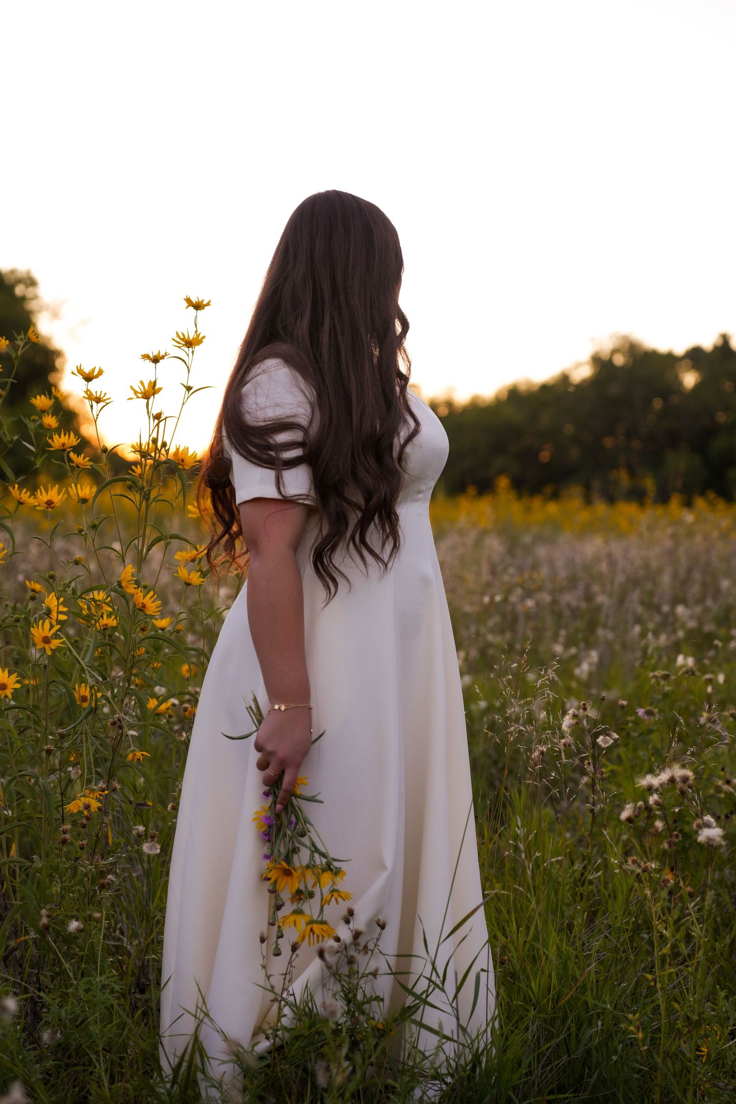 White dress detail among yellow and purple wildflowers in a summer meadow.