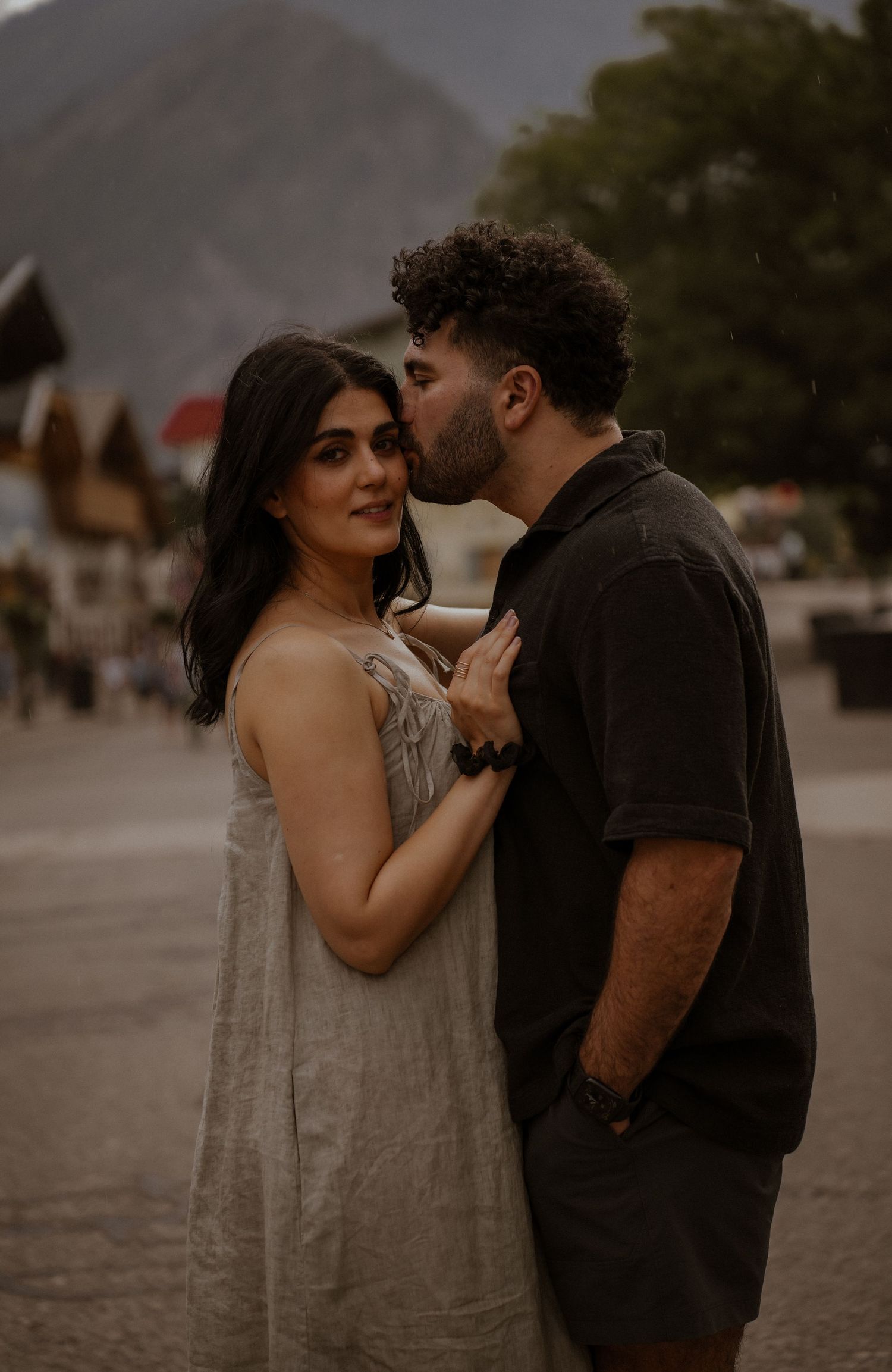 A couple shares an intimate moment in a moody outdoor photoshoot with warm tones and natural lighting.