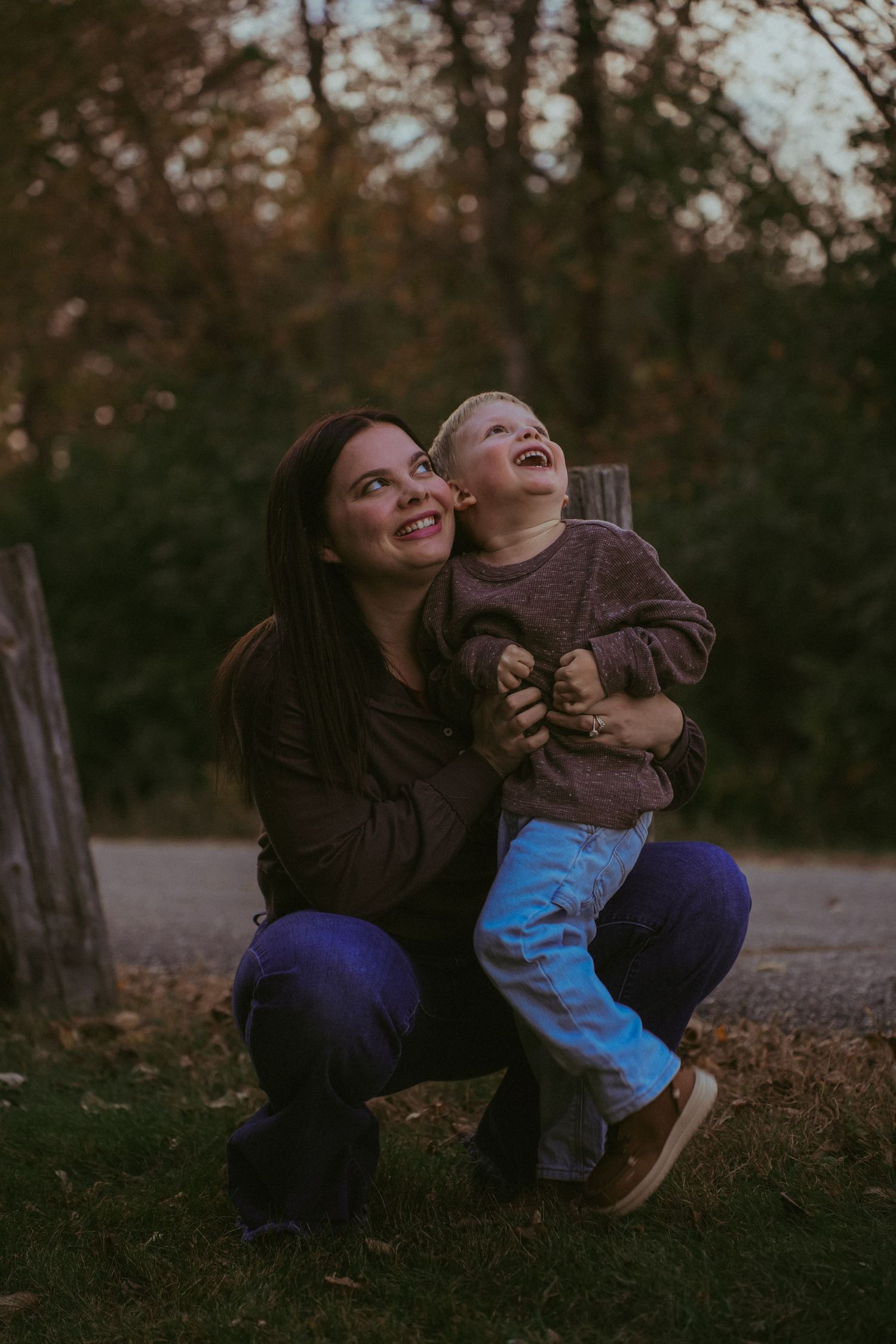 Parent and child share joyful laughter while playing outdoors at sunset.