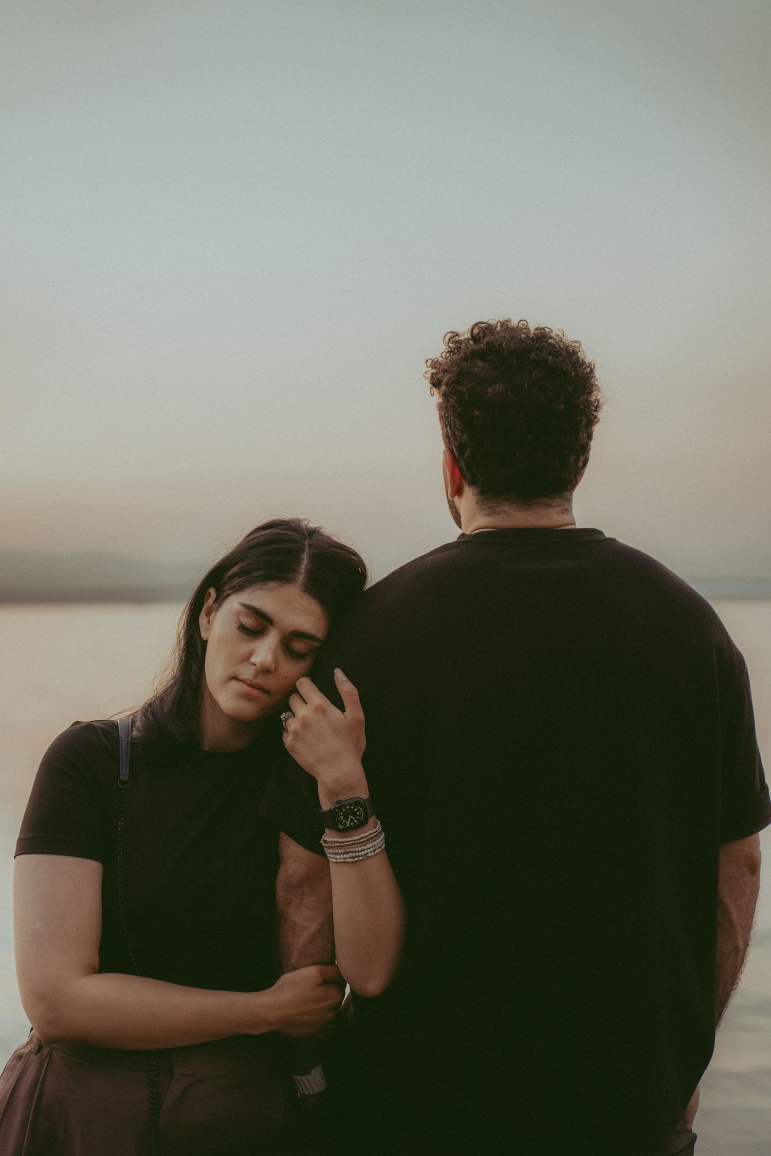 Couple embraces in intimate moment during sunset photoshoot with muted tones.