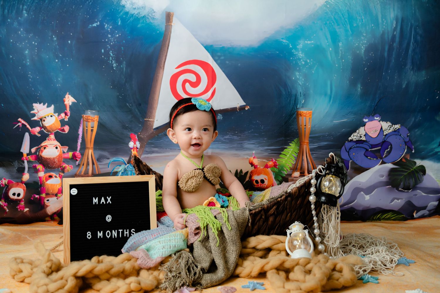 Moana-themed photo setup with ocean backdrop, sailboat, and tropical decorations.