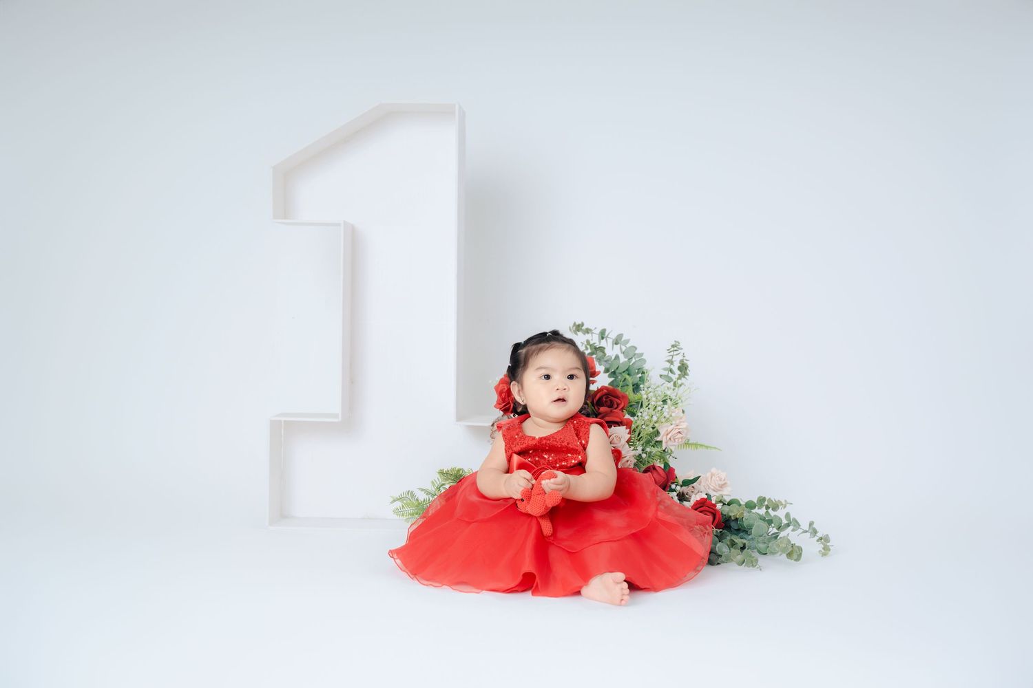 White number one decoration with red and pink floral accents against a light background.