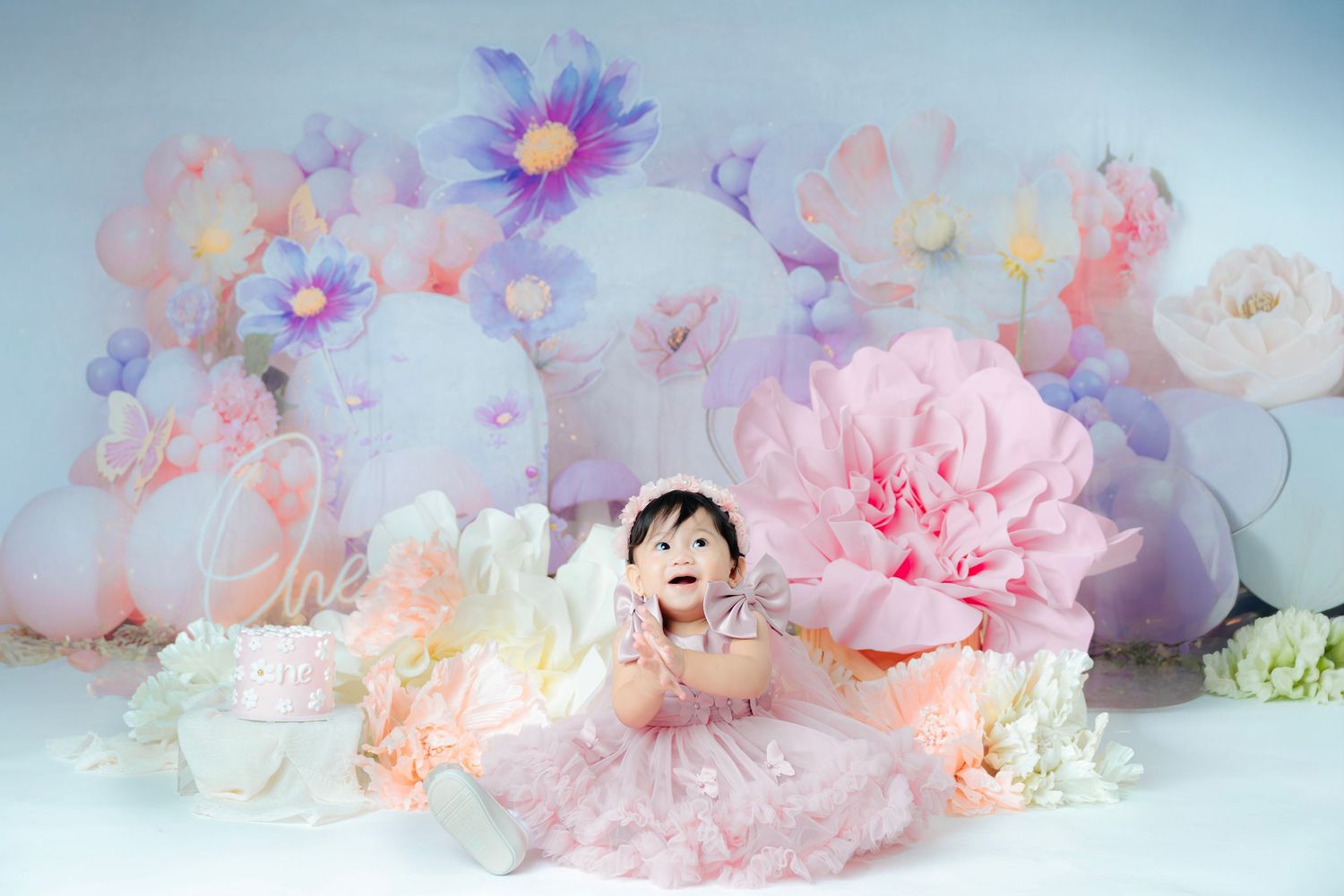 Delicate pink and purple flowers with soft petals arranged in a dreamy pastel composition against a light background.