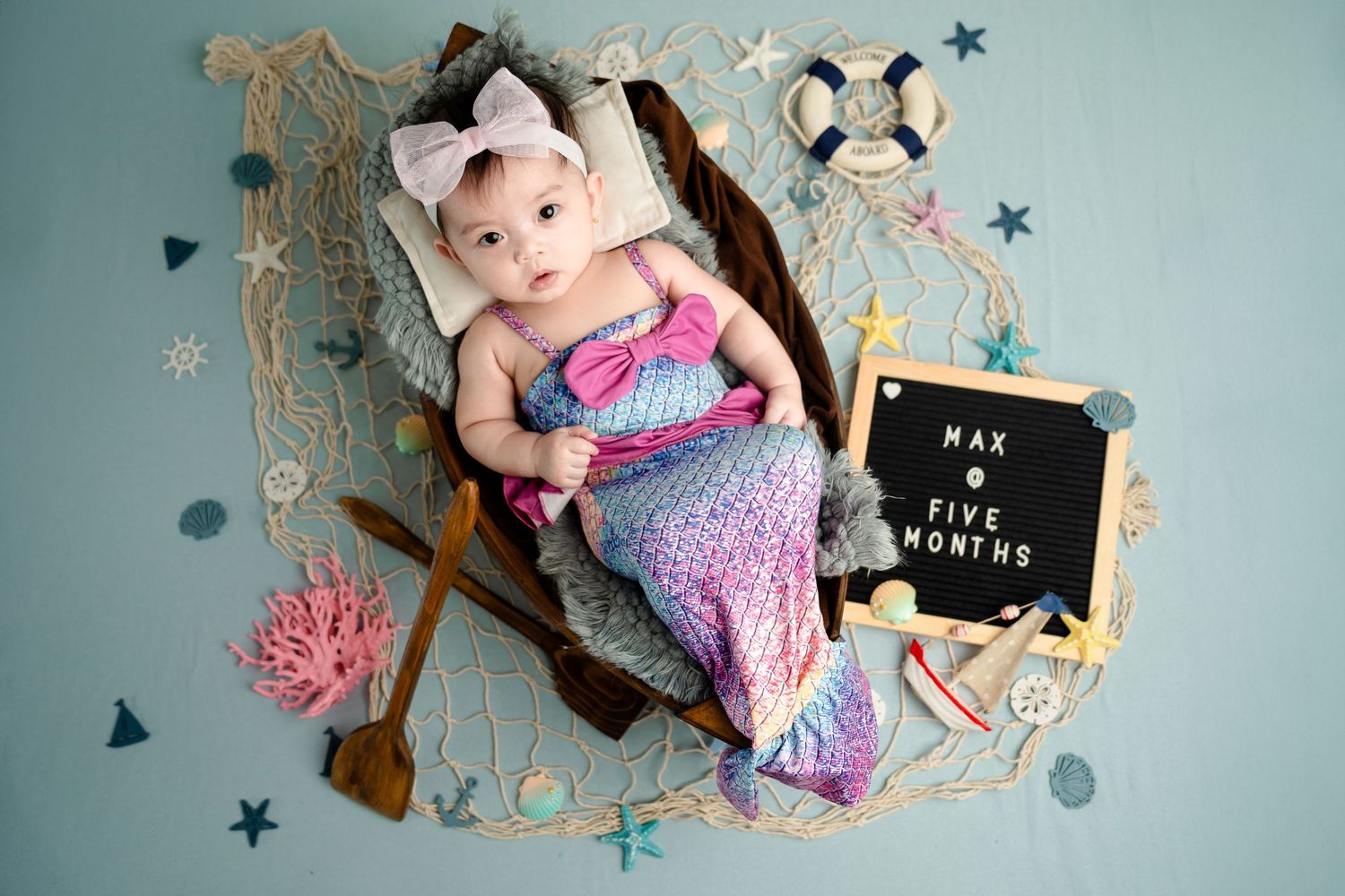 Nautical themed photo with mermaid props, seashells, and blue star decorations.