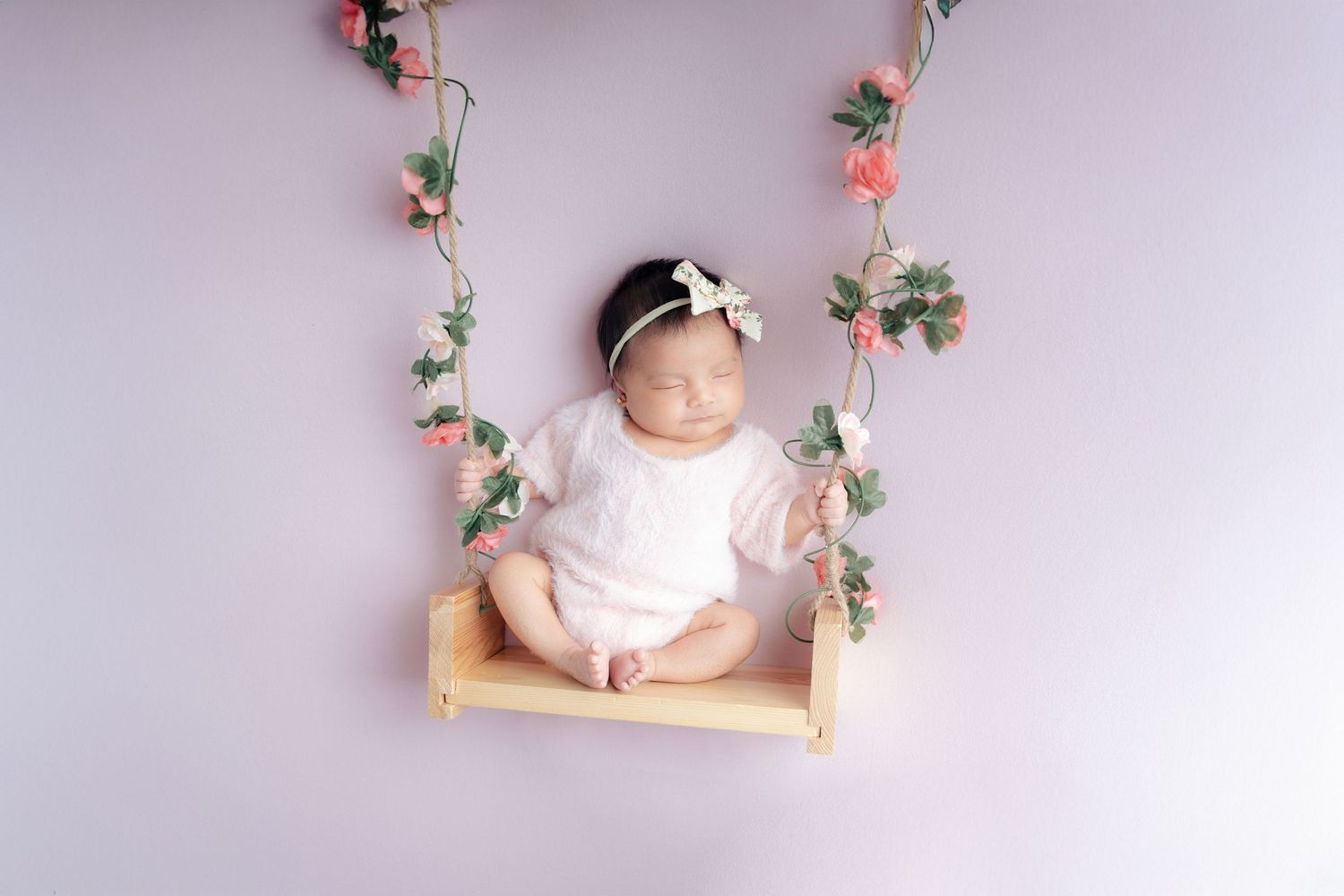 A dreamy floral composition with pink roses and delicate flowers arranged on a light gray background.