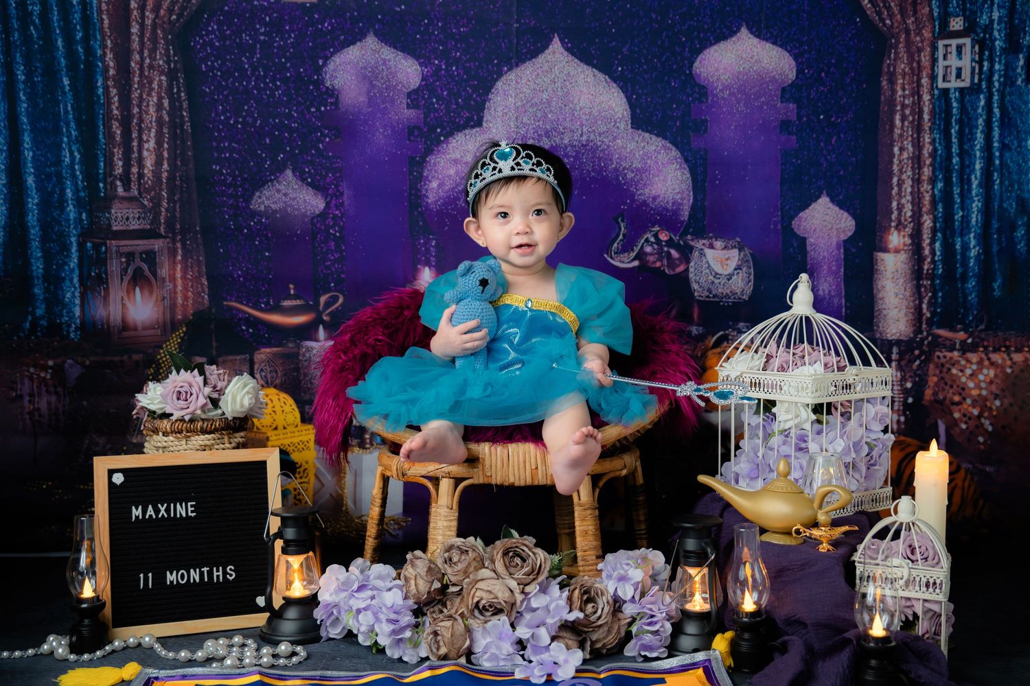 Arabian nights themed photo setup with purple backdrop, birdcage and ornate decorations.