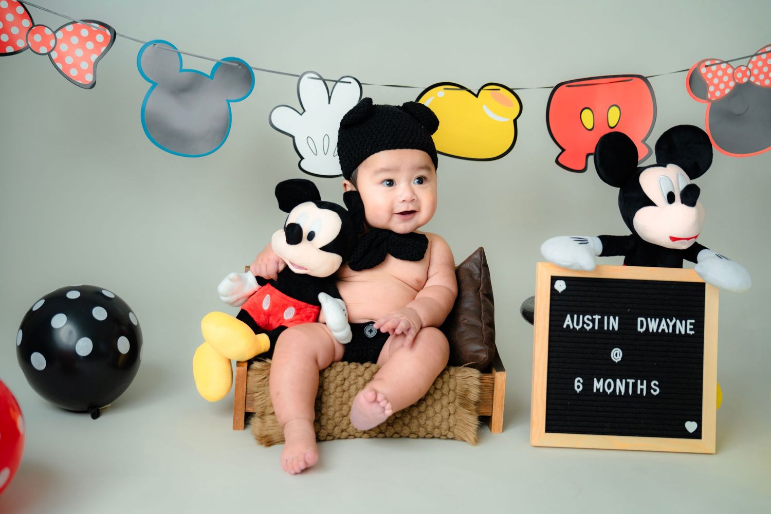 Mickey Mouse themed baby photoshoot with character cutouts and polka dot decorations.