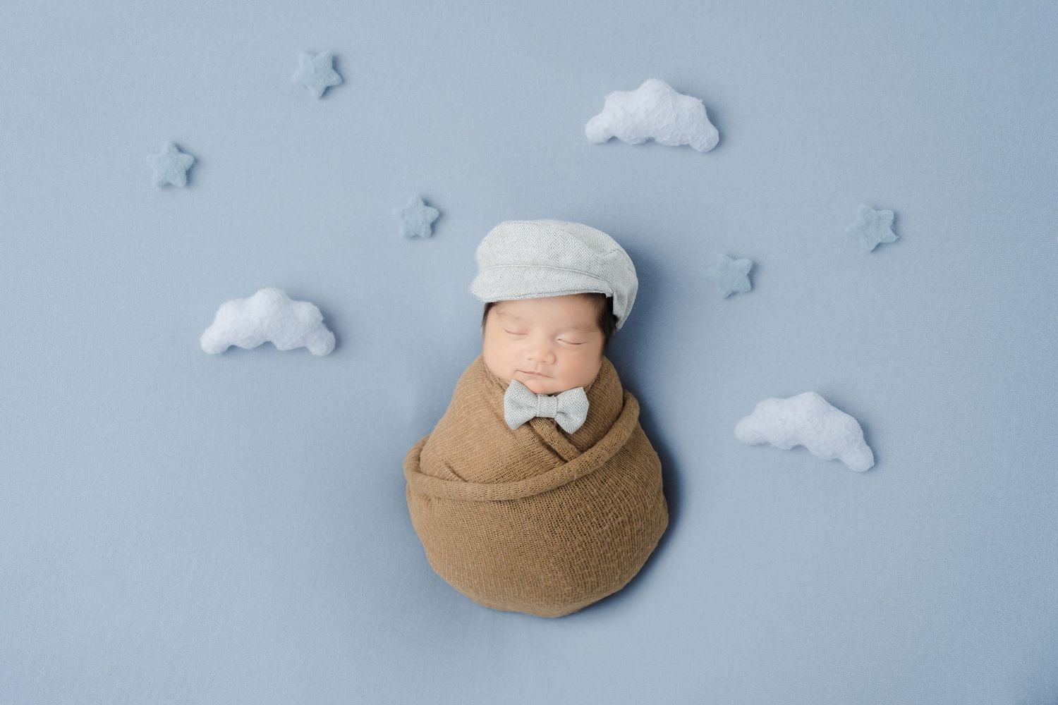 A series of photos showing a brown bucket hat with white heart detail against a blue background with cloud decorations.
