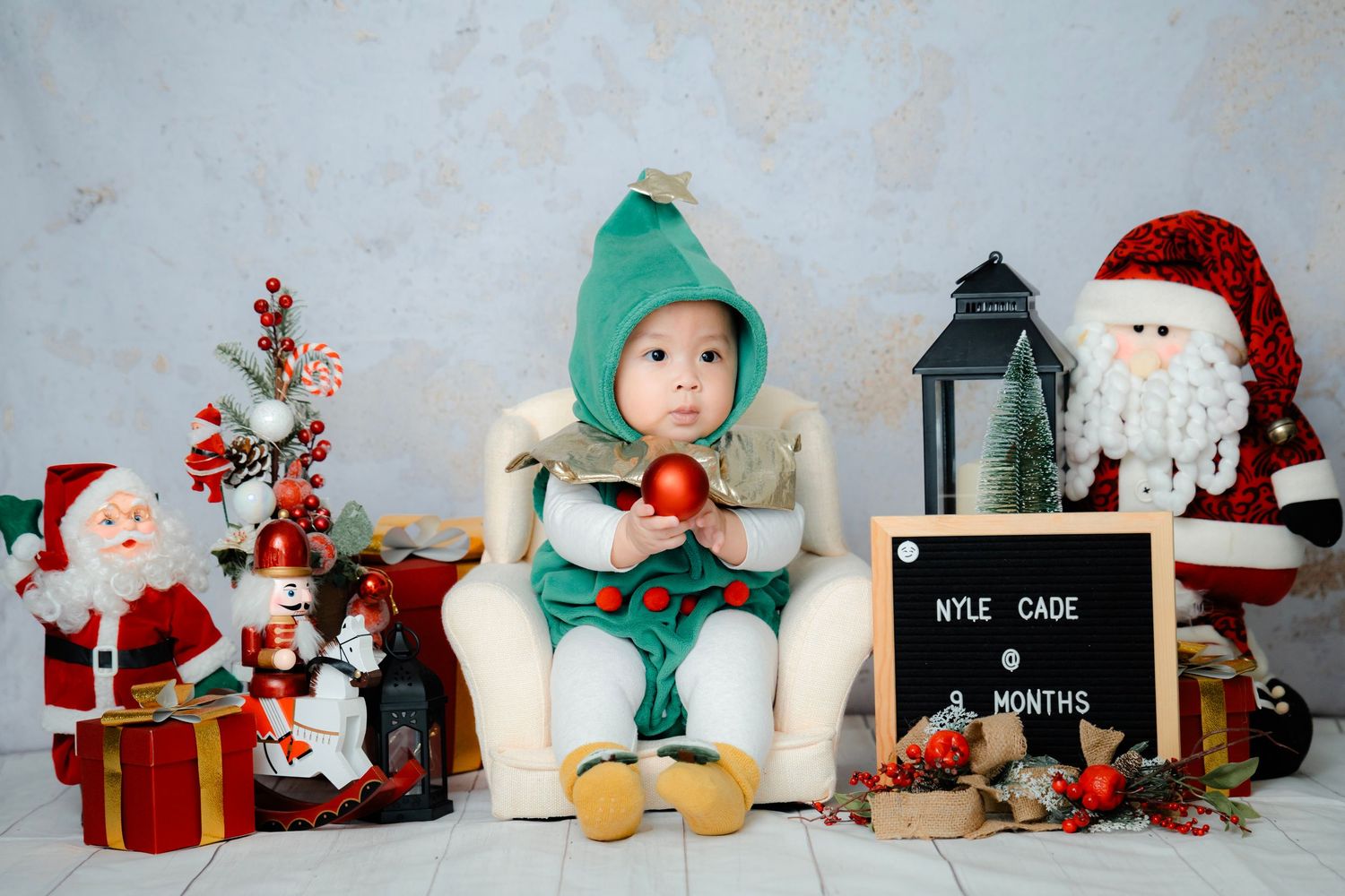 A festive Christmas scene with plush toys, Santa decorations, and red gift boxes arranged on a white background.