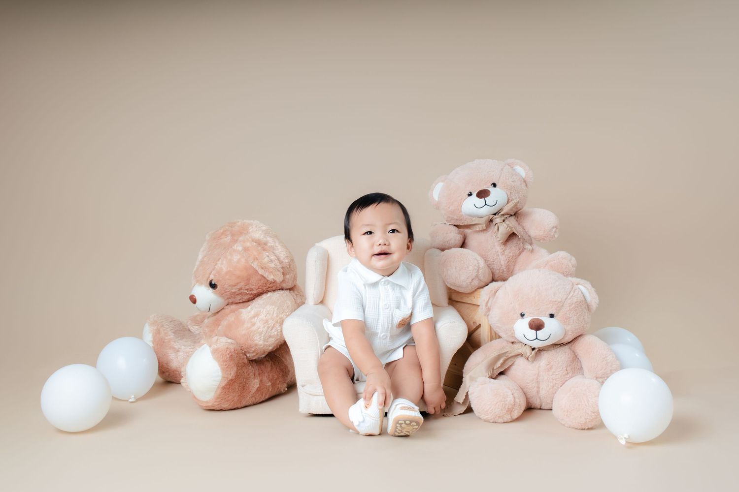 A series of connected photos showing teddy bears and stuffed animals arranged with a baby on a beige backdrop.