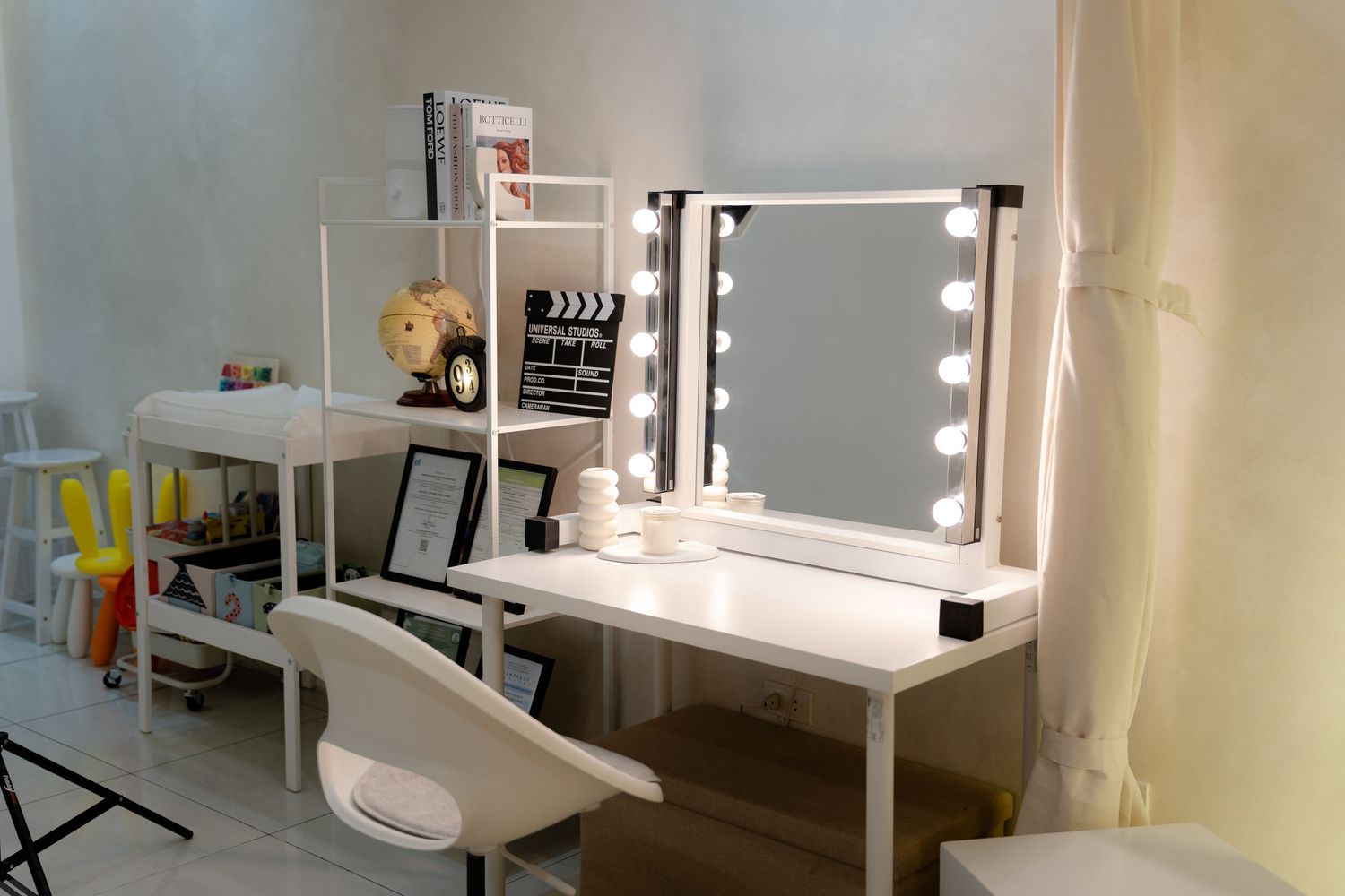 Professional makeup station with lighted mirror, white desk, and organized accessories in a bright studio space.