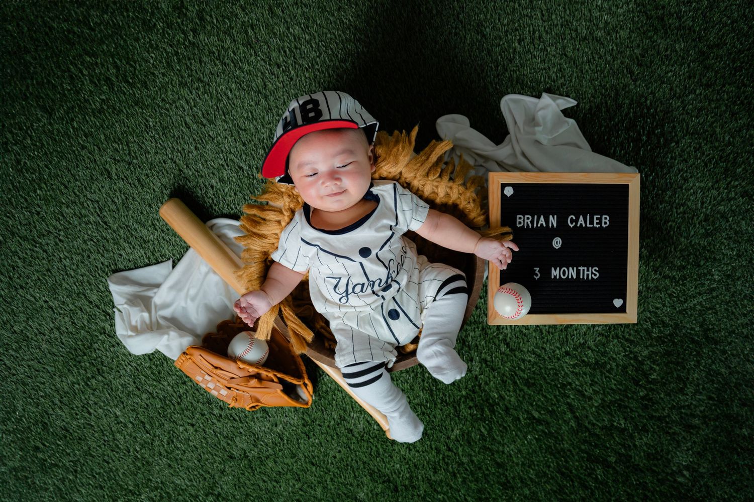 Sports themed milestone photos on green turf with baseball equipment and memorabilia.