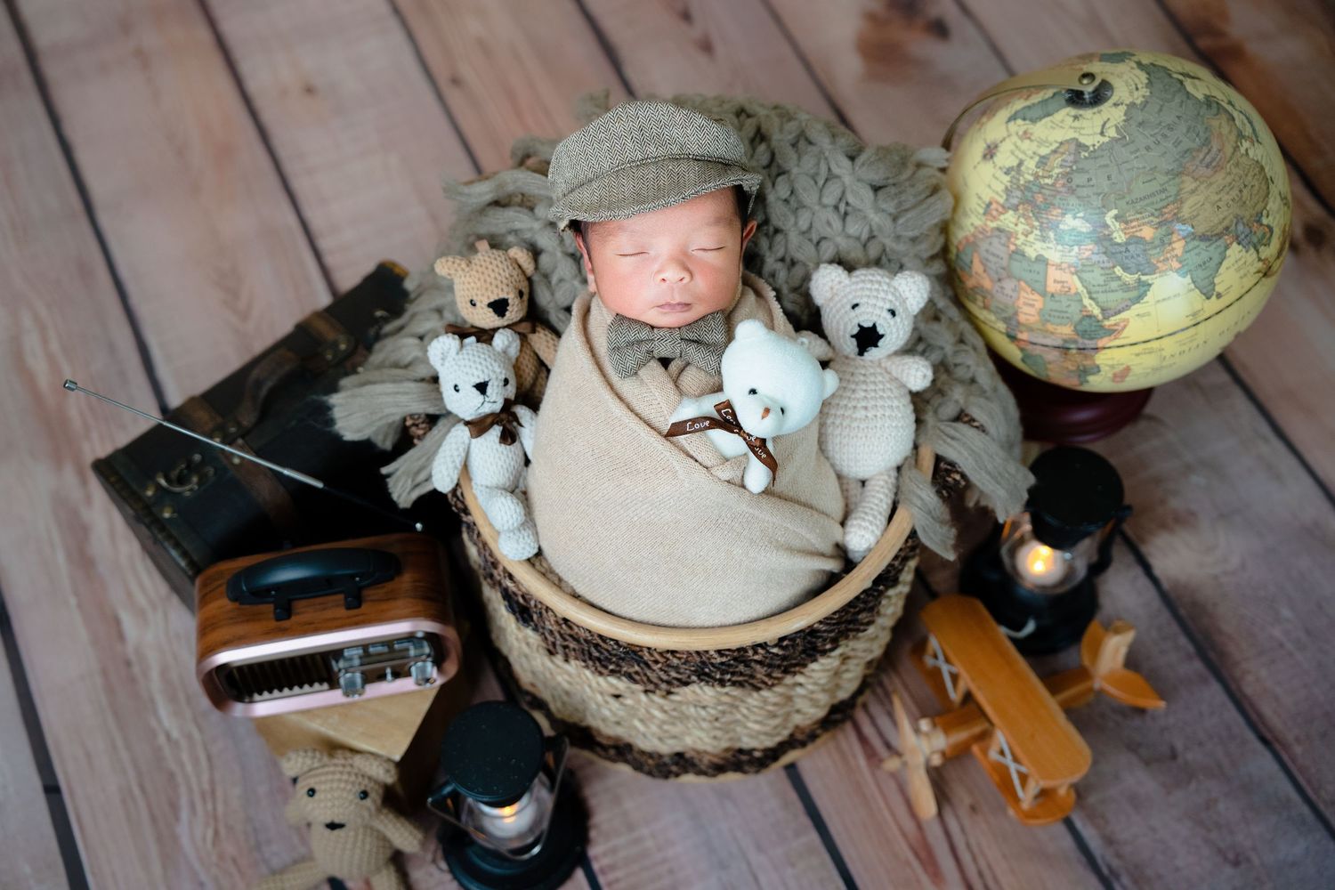 Vintage toys and stuffed animals arranged around a globe on wooden floor with a rustic drum and camera.
