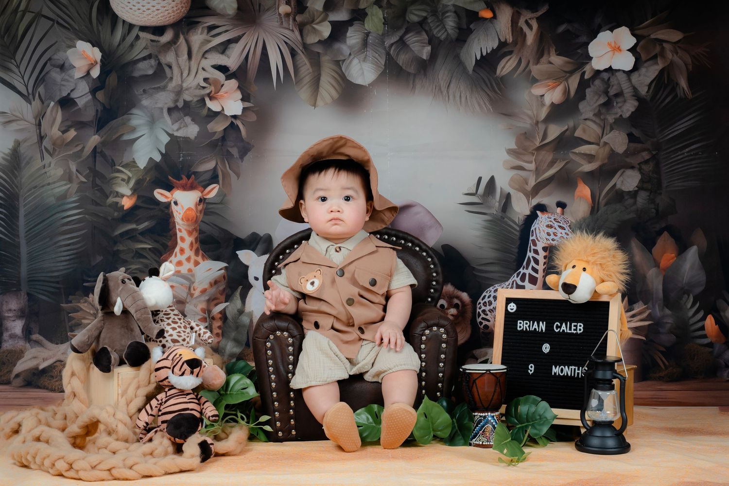 Safari themed photo setup with giraffe plush toy and tropical foliage backdrop.