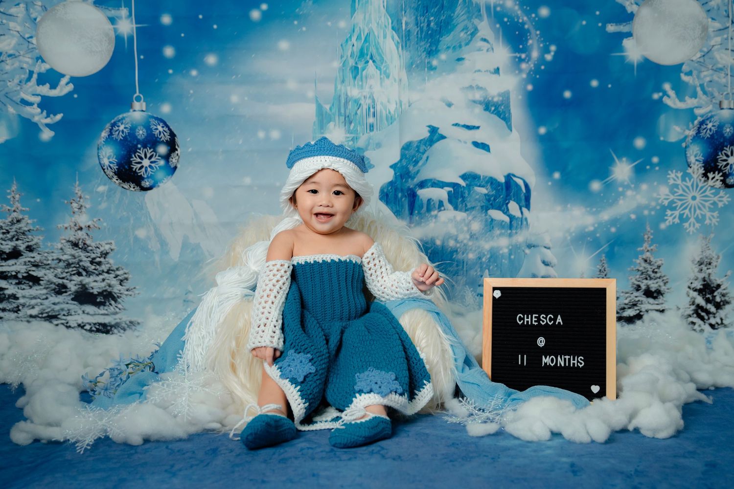 Winter wonderland themed milestone photo setup with snowy backdrop and decorations.