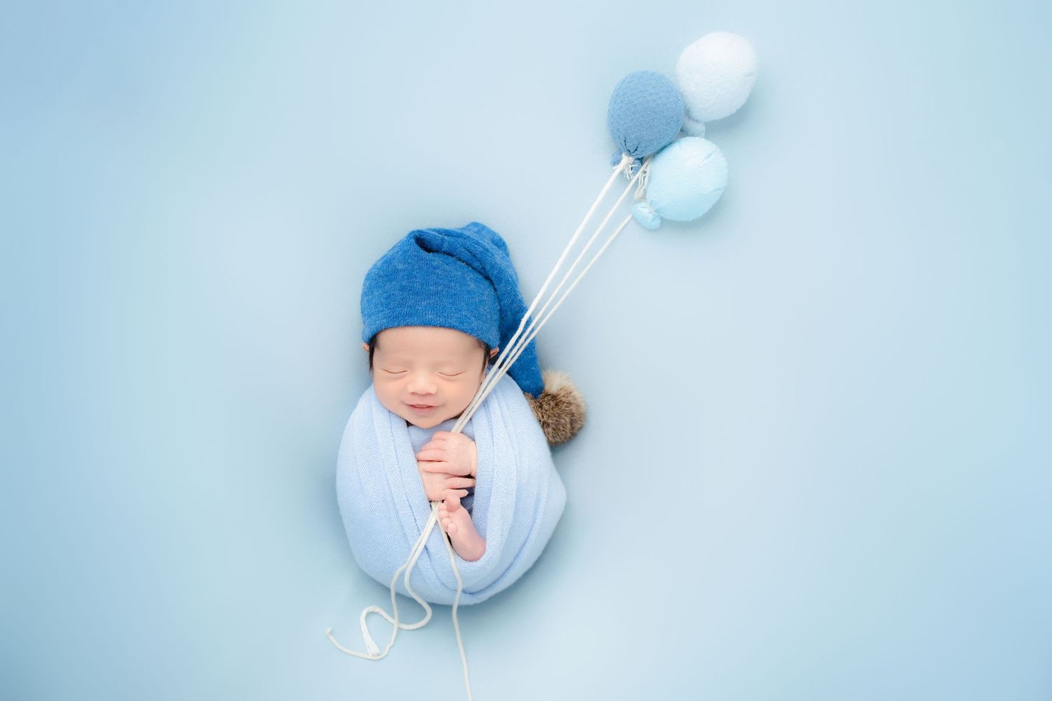 Sleeping baby with white balloons against dreamy blue background.