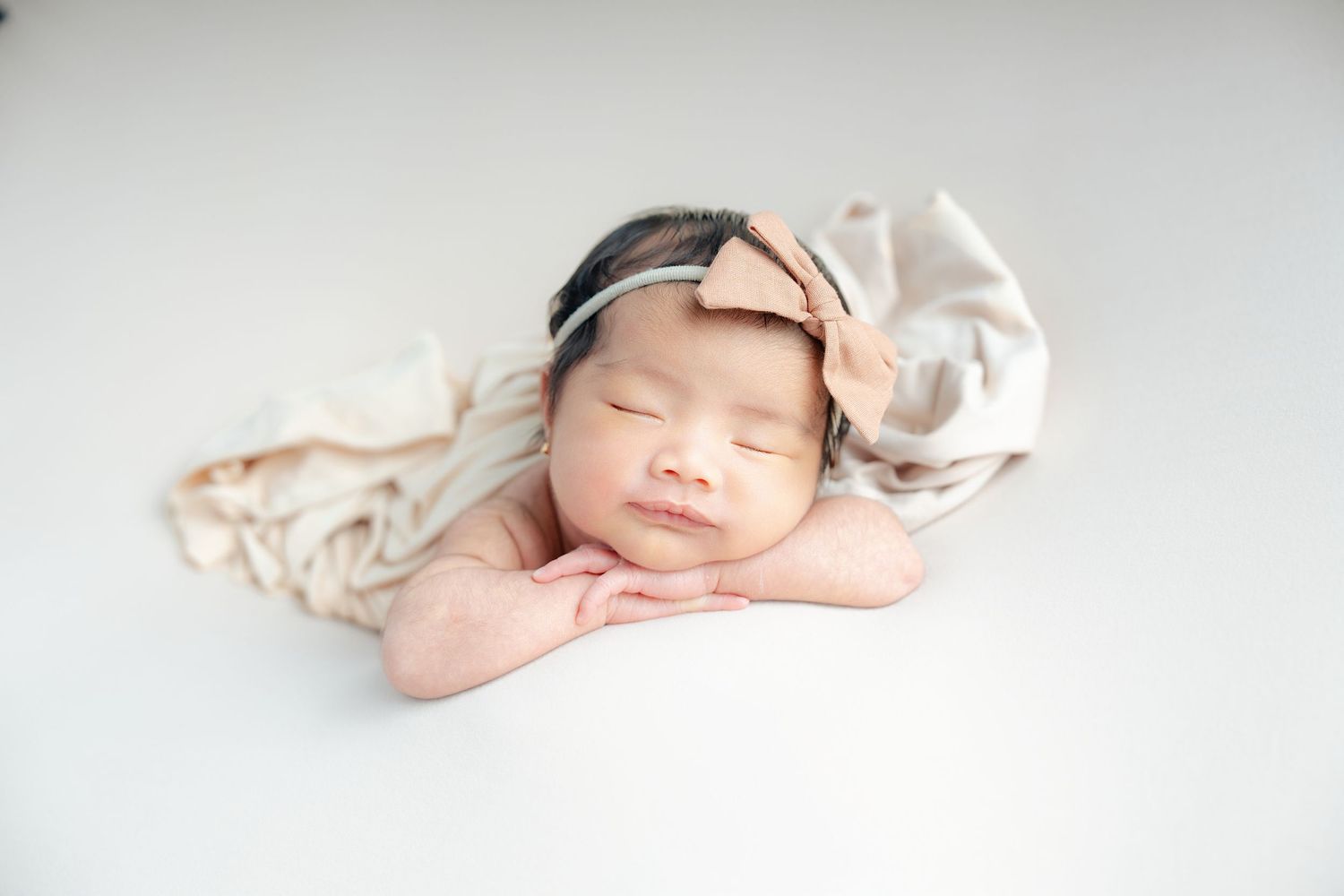 Sleeping newborn baby in soft pink swaddle blanket lying on white background.