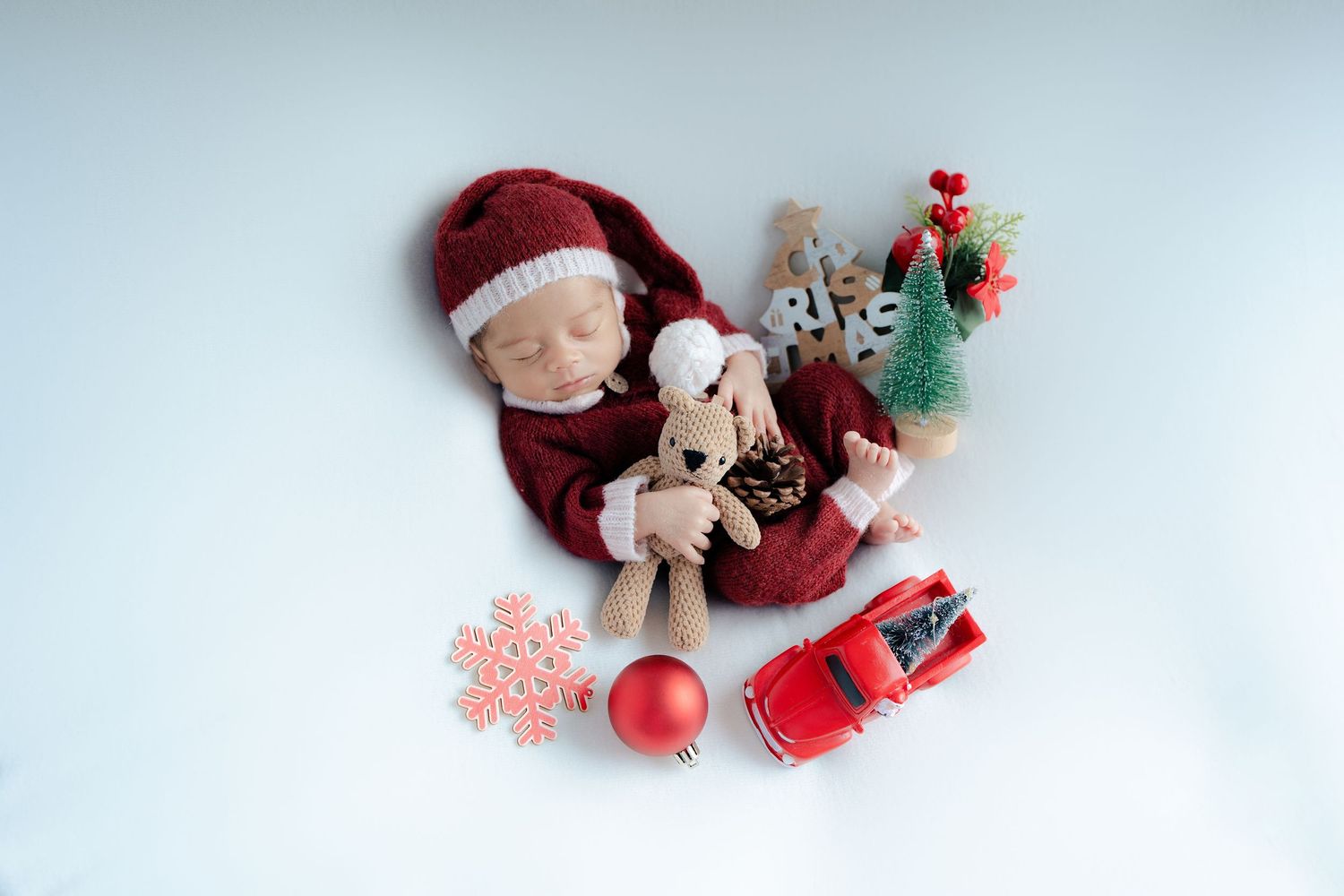 Christmas decorations with red car toy, plush toy, snowflake ornament and red bauble on white background.