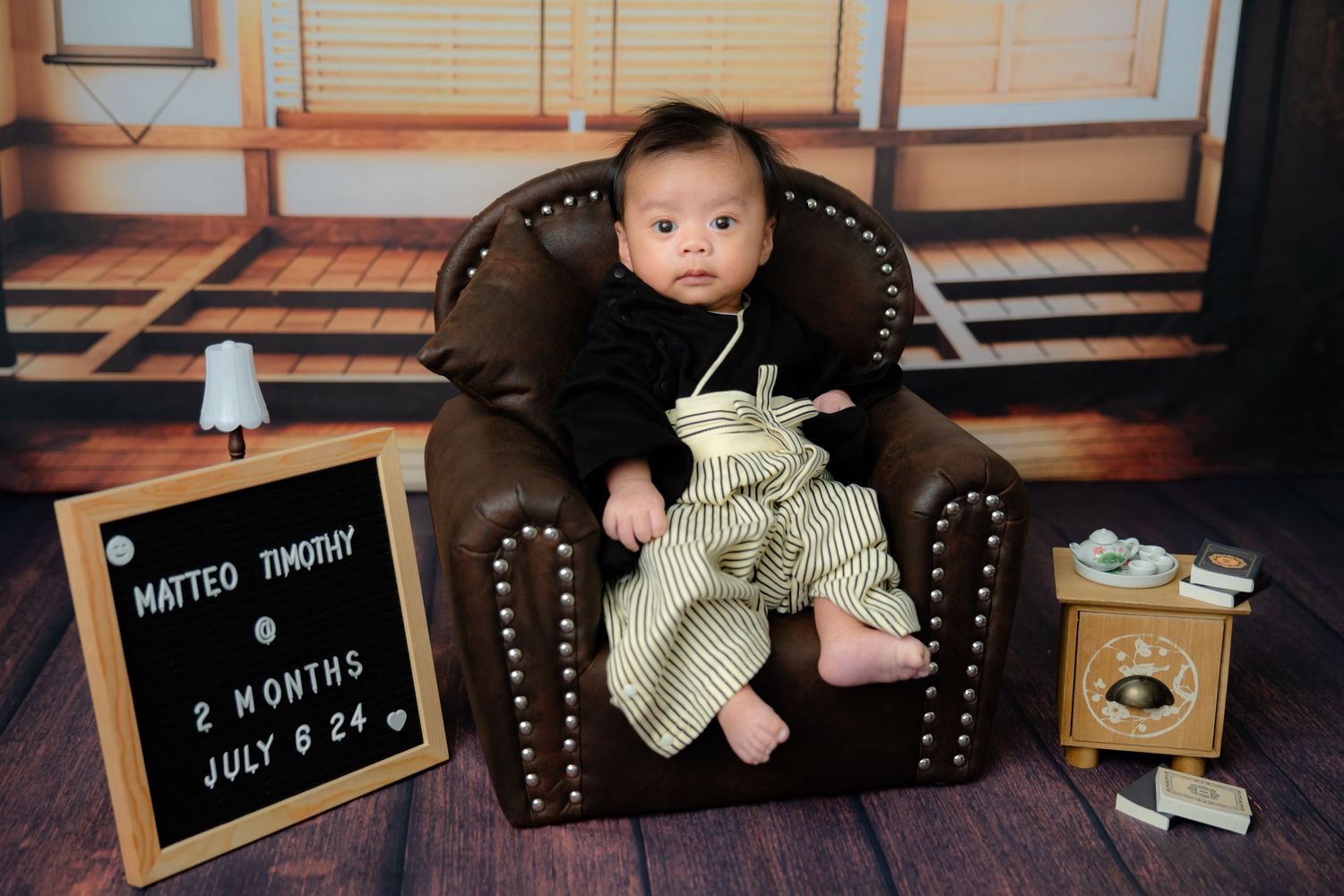 Vintage style photo setup with dark leather armchair and letterboard in warm tones.
