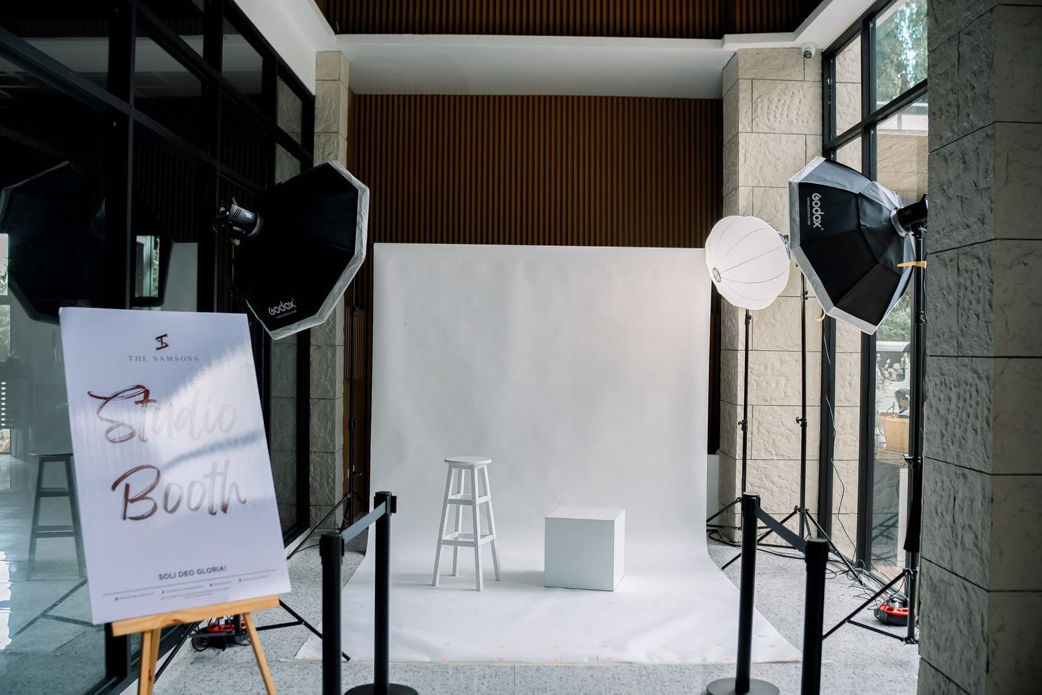 Professional photography studio setup with white backdrop, lighting equipment, and a sketch pad on an easel.