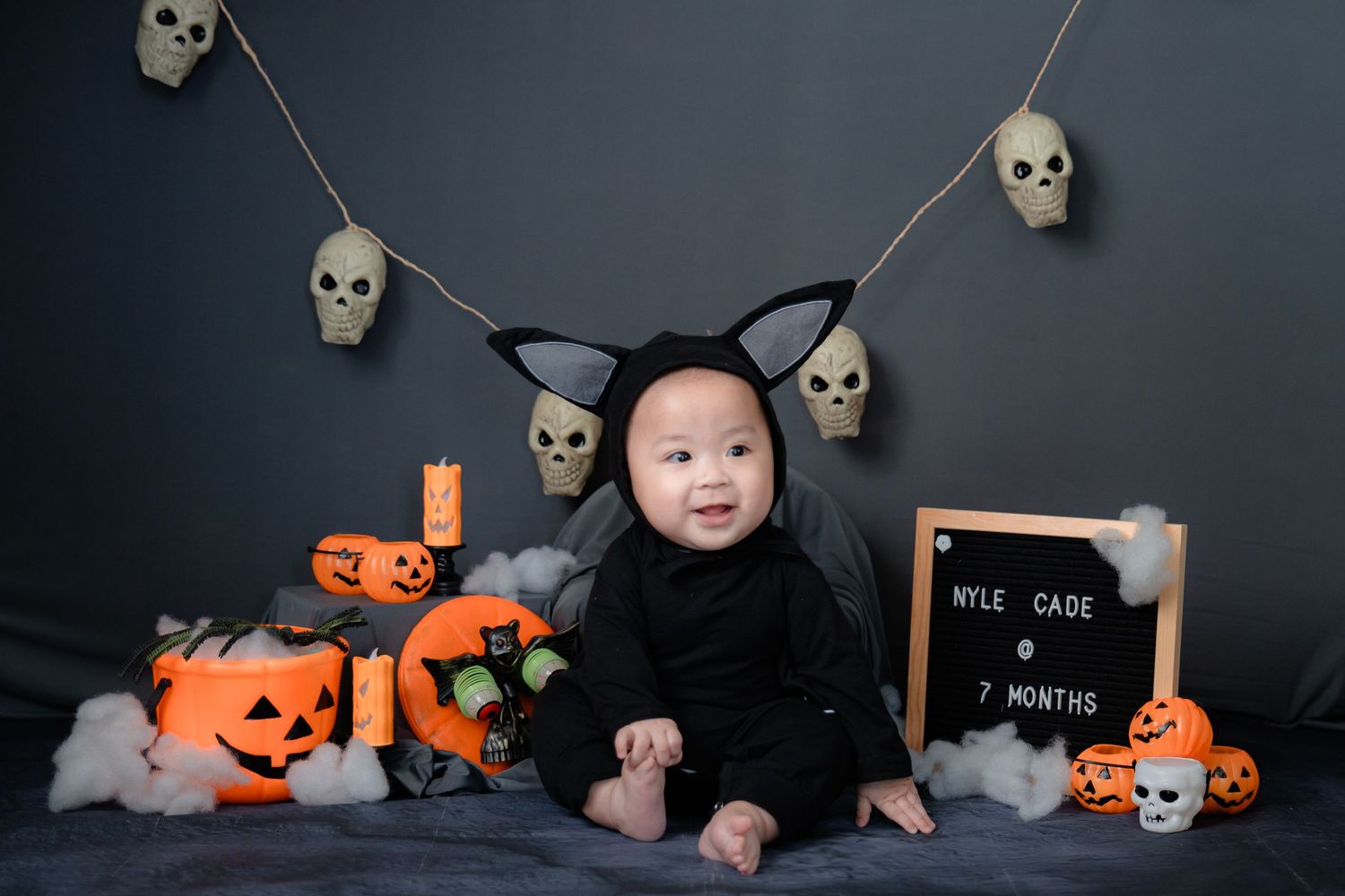 Halloween themed photo setup with spooky skulls, pumpkins, and orange accents on dark background.