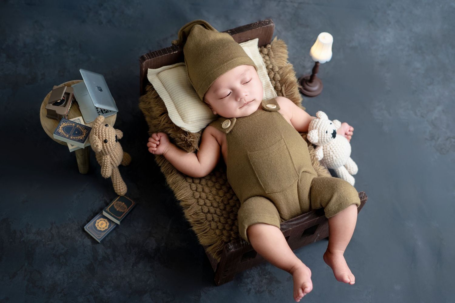 Baby in tan outfit sleeping on cushion with stuffed animals and vintage decor.