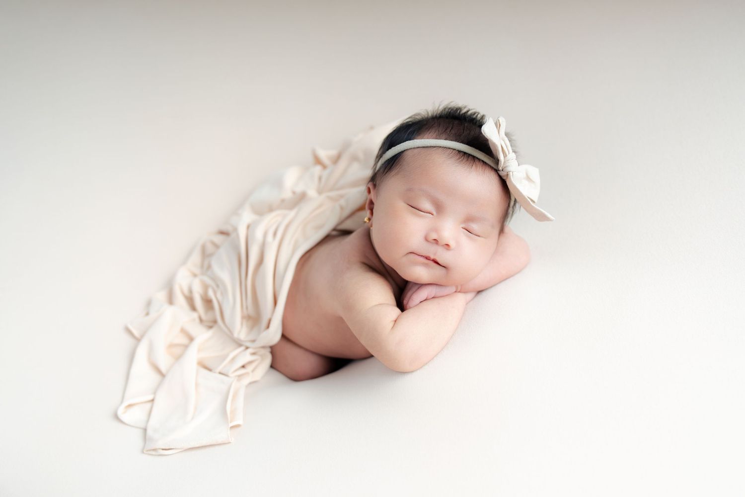 Four serene newborn baby photos in soft beige tones show peaceful sleeping poses on light backgrounds.
