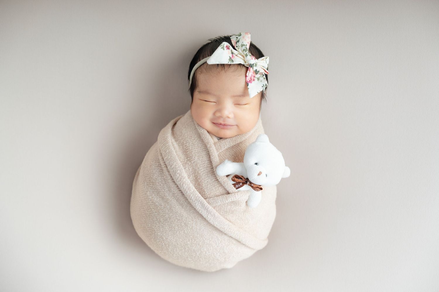 A series of six artistic newborn photos showing a sleeping baby wrapped in soft white fabric against a light background.