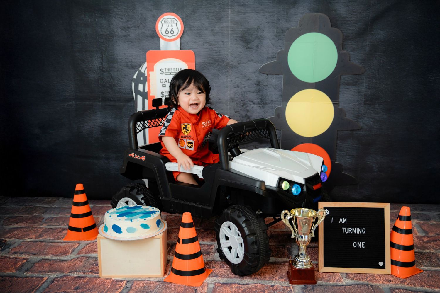 Stylized racing photo setup with traffic cones, toy car and checkered accessories against dark background.