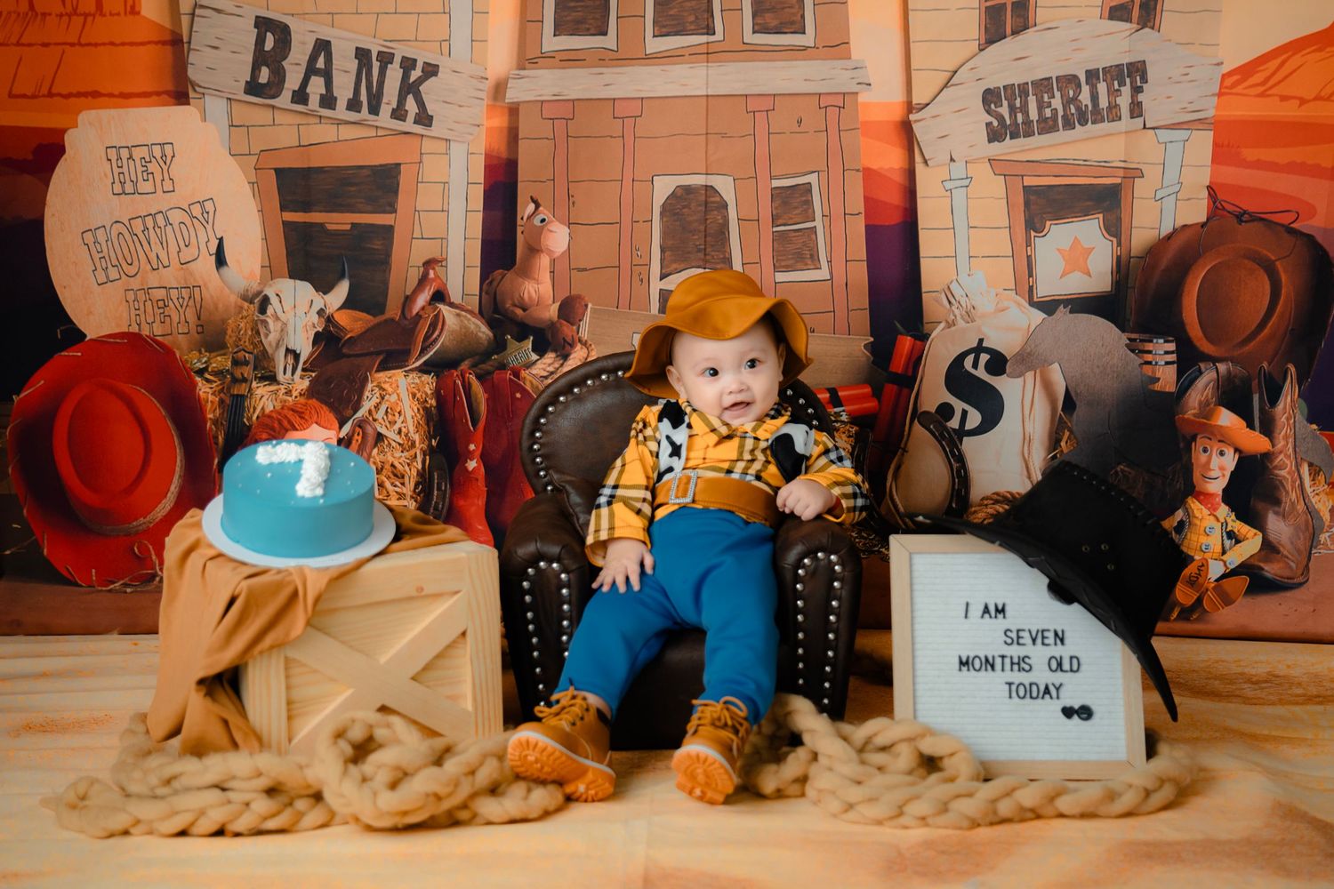 A western-themed photo setup with a toy cowboy sitting in a leather chair surrounded by bank and sheriff props.